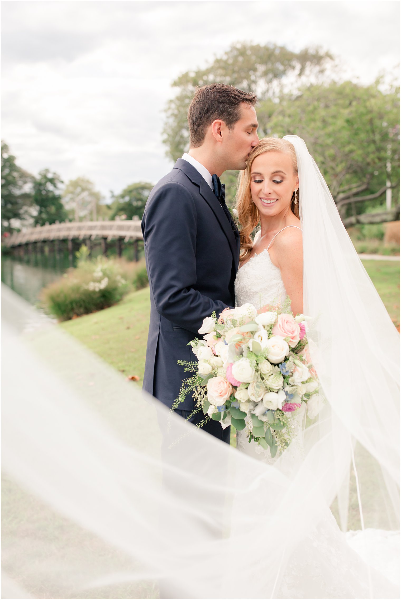 bride and groom pose with veil wrapped around them