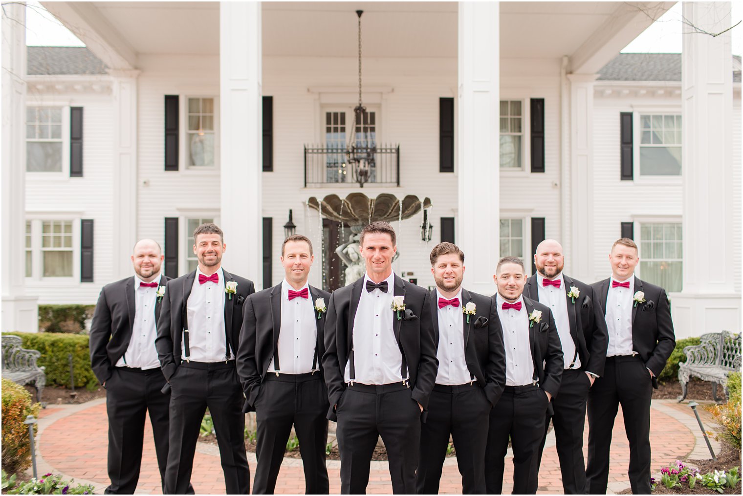 groom poses with groomsmen in suits with suspenders outside Park Savoy Estate