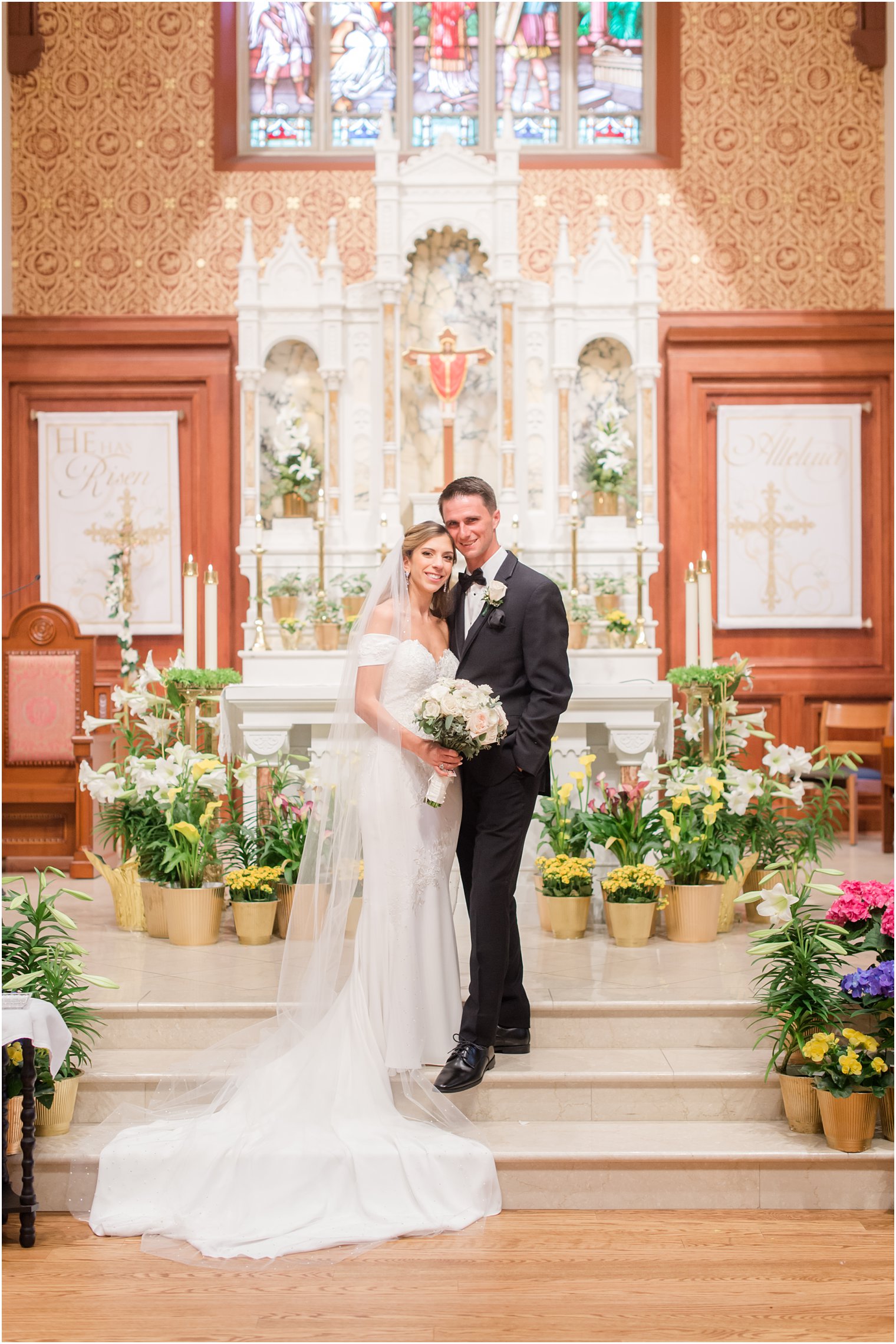 bride and groom pose on altar in Catholic Church after wedding ceremony 