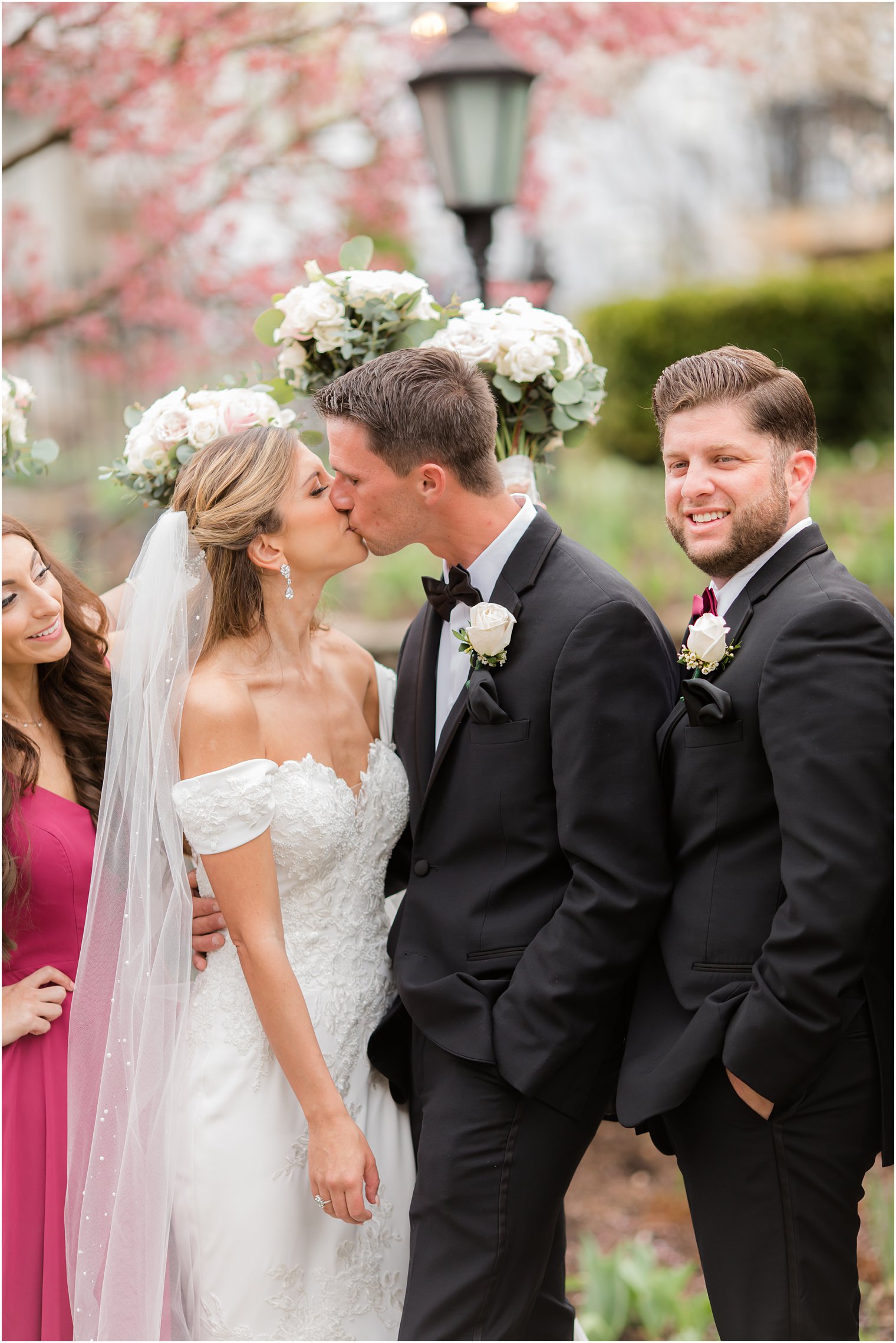 bride and groom kiss with bridal party cheering them on in New Jersey 