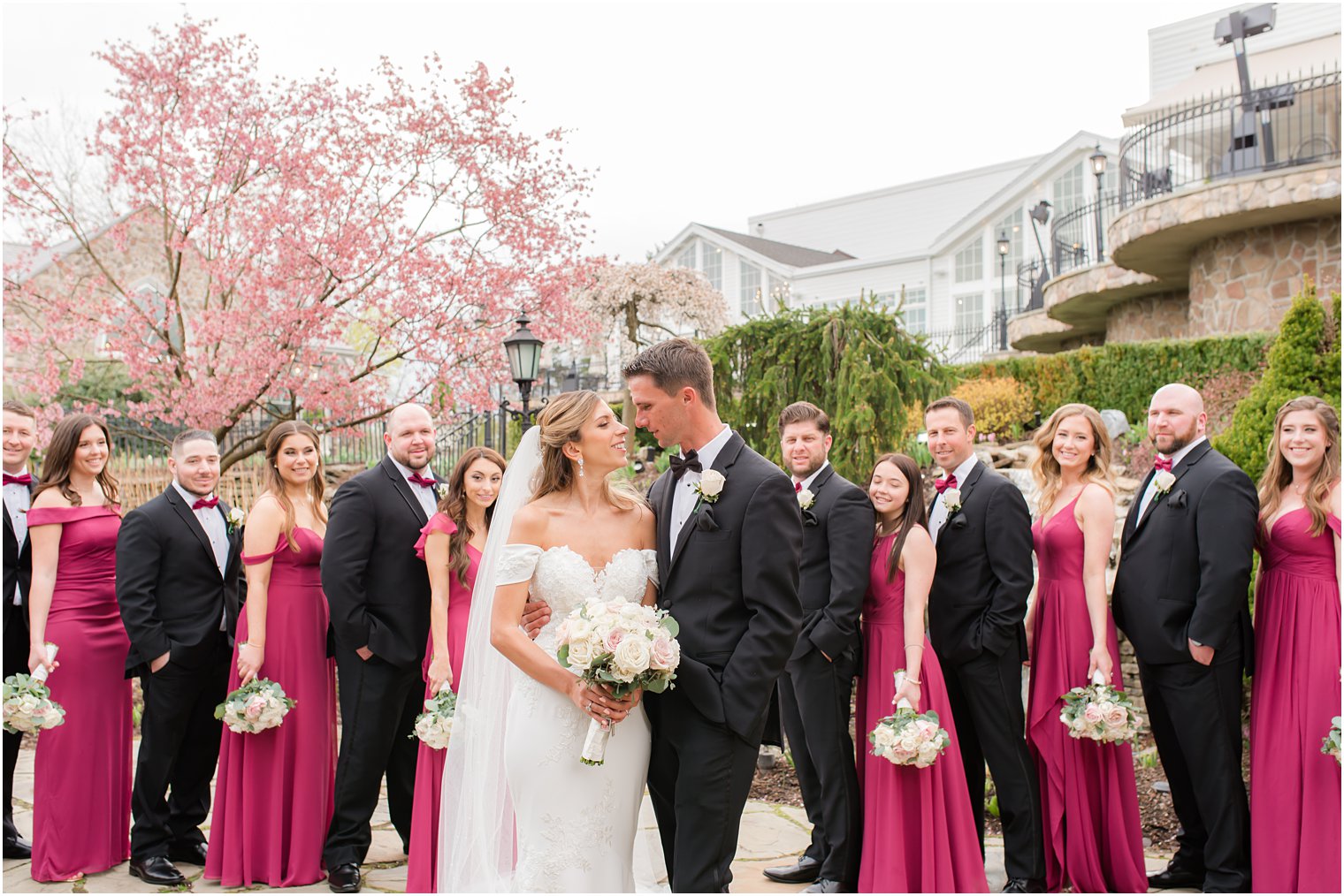 bride and groom look at each other with bridal party in cranberry looking at them 