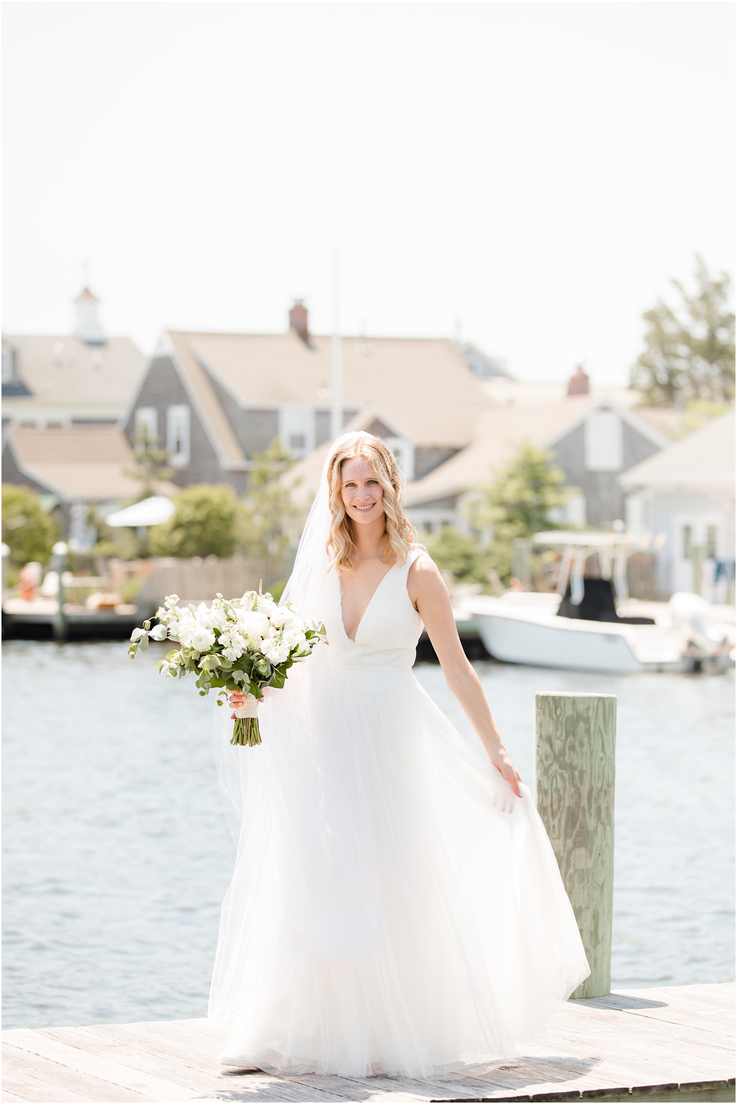 bride twirls in wedding dress holding bouquet of all white flowers on dock in Bay Head NJ