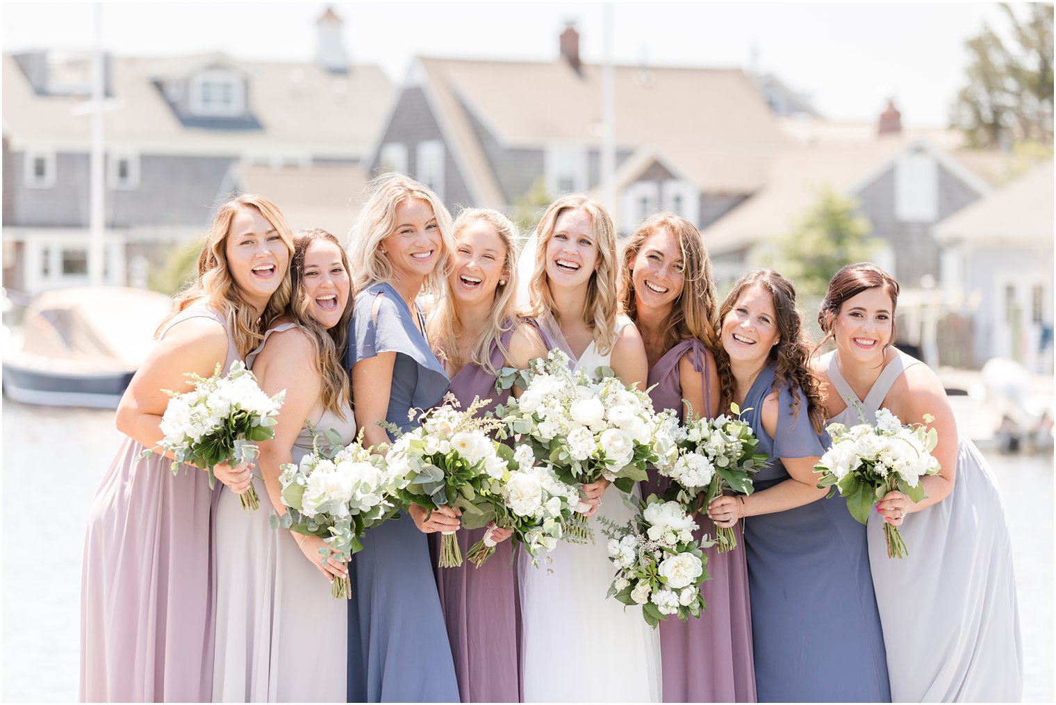 bride laughs with bridesmaids in purple and blue gowns 