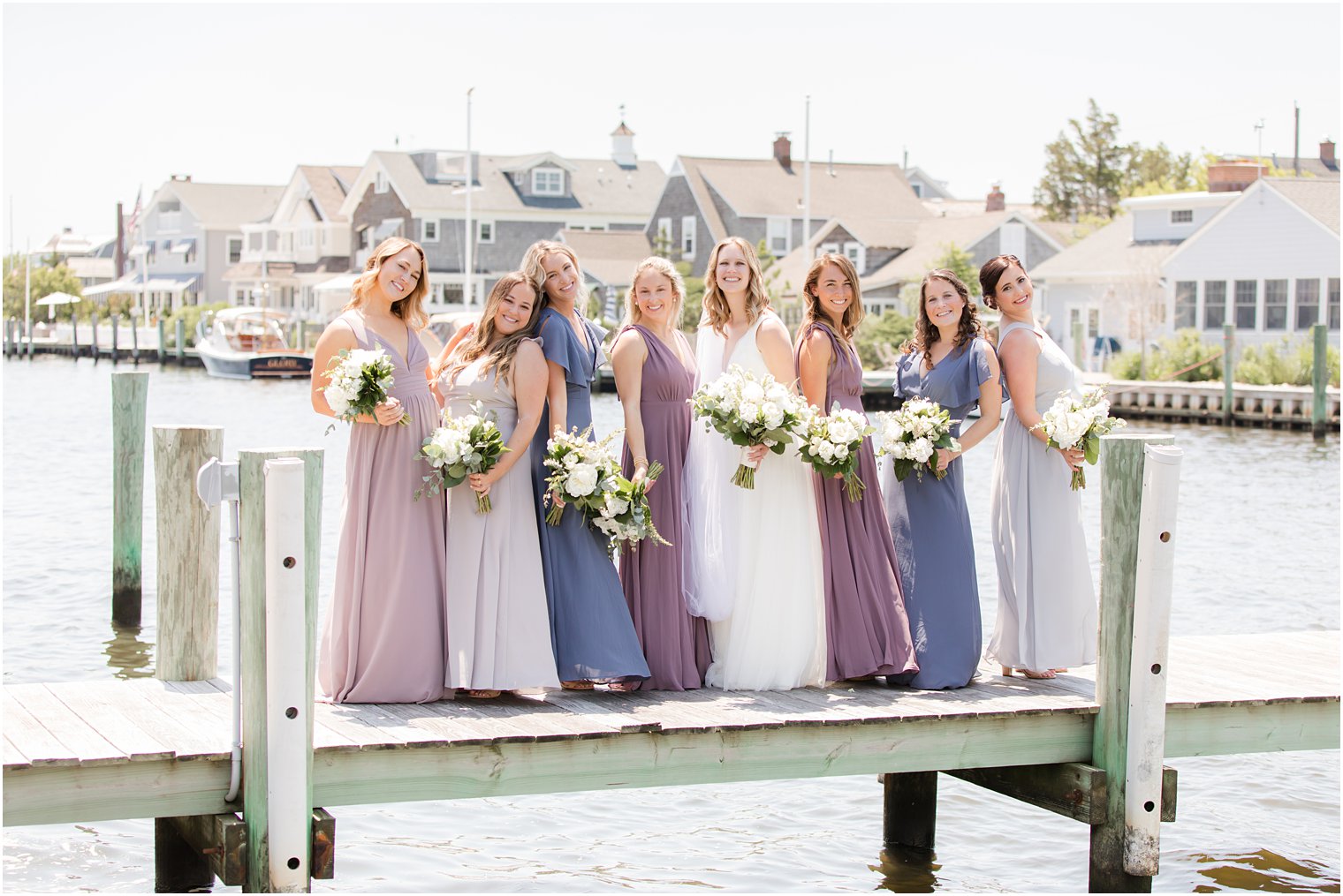 bride and bridesmaids in mismatched spring gowns pose and dock in NJ