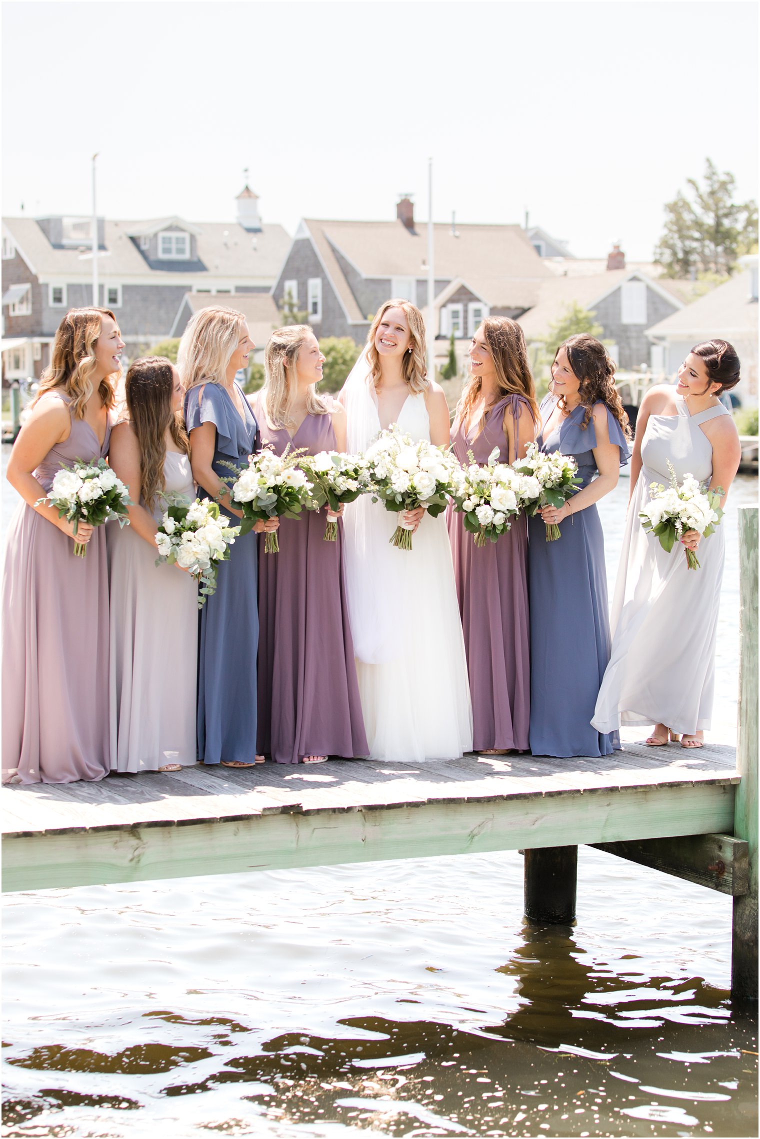 bride poses with bridesmaids in mismatched gowns on dock in Bay Head NJ