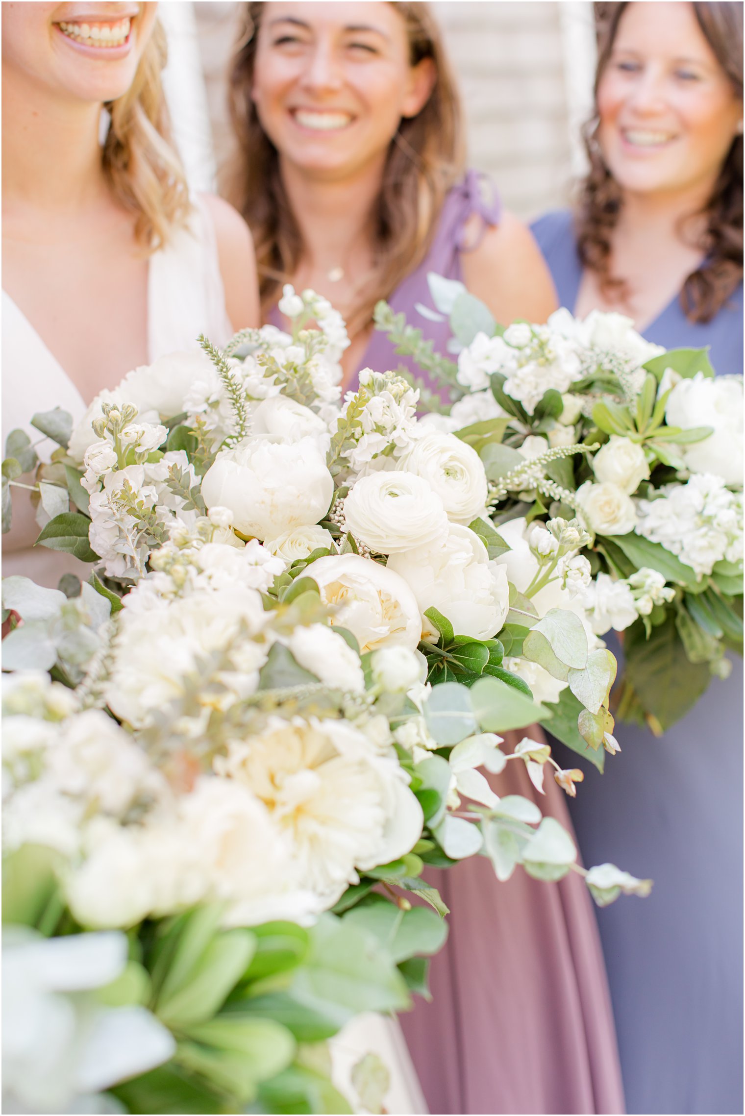 bridesmaids hold bouquets of white peonies and ranunculus 