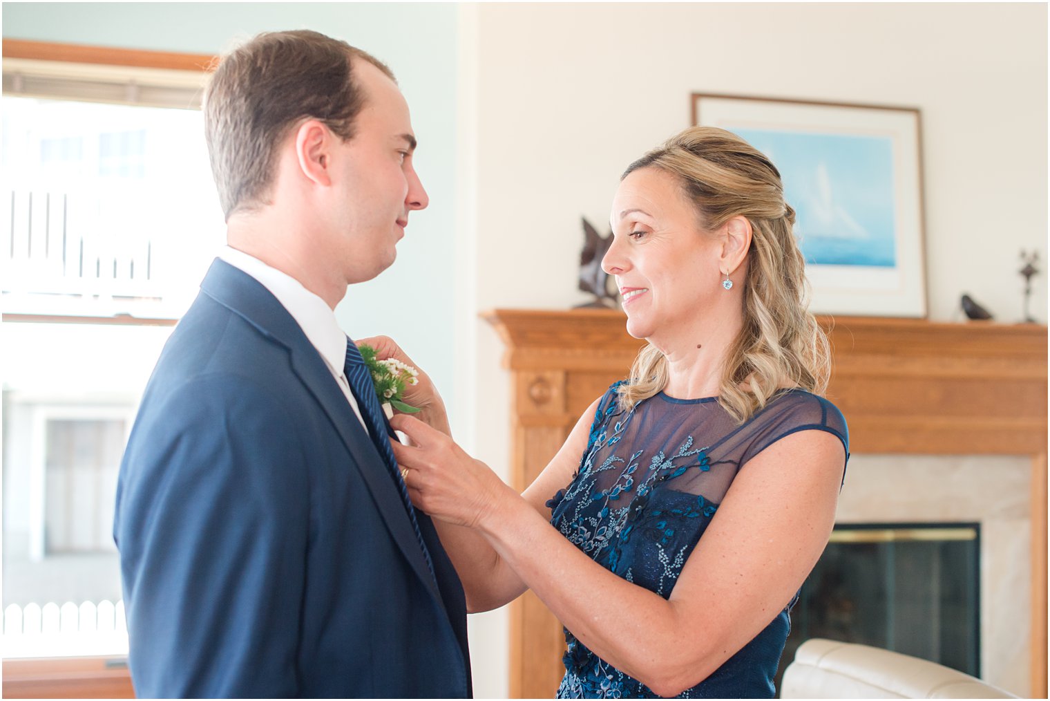 mother of groom adjusts boutonniere for groom in navy suit 