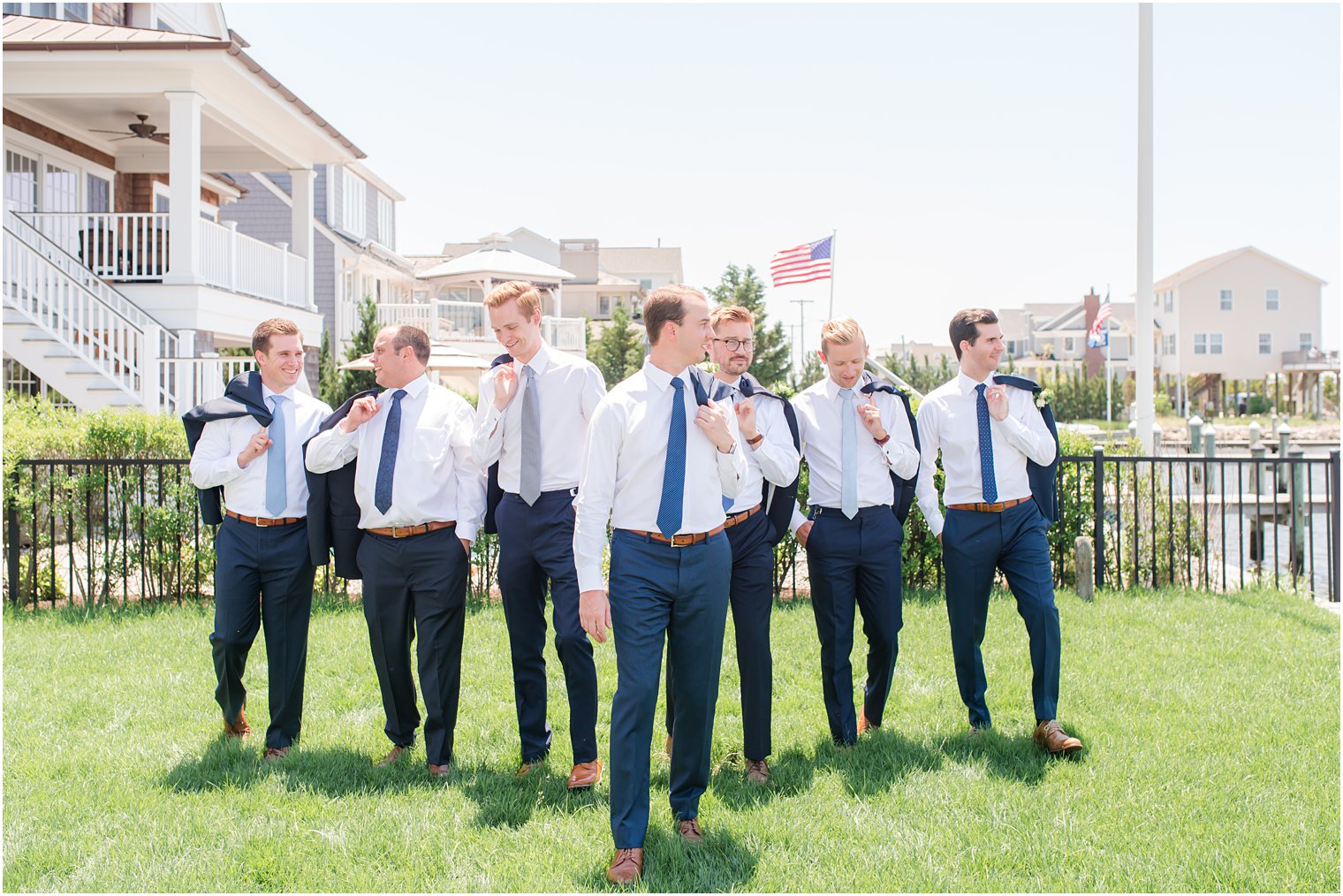 groom and groomsmen pose with jackets over shoulders before NJ wedding 