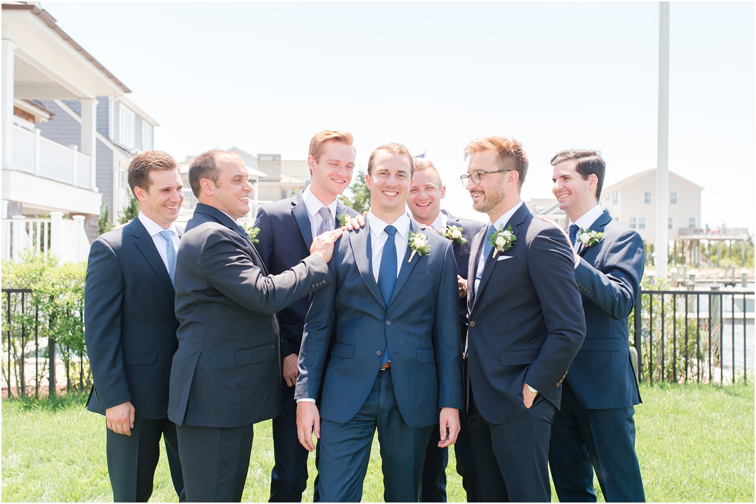 groom poses with six groomsmen in navy suits