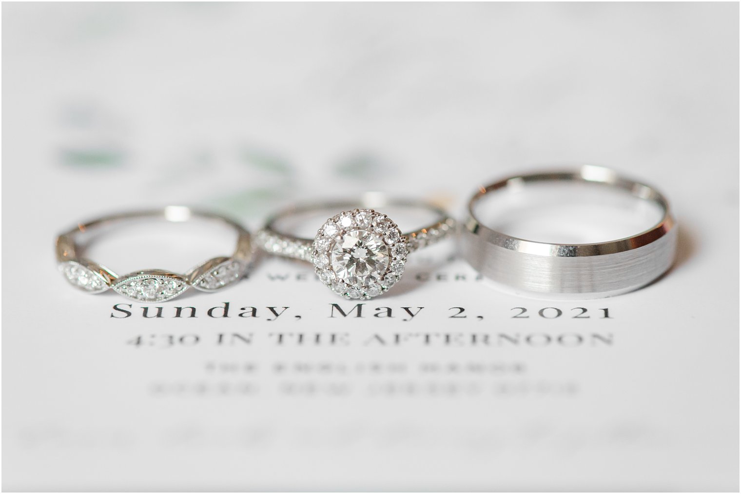 wedding bands rest on wedding invitation for spring wedding day