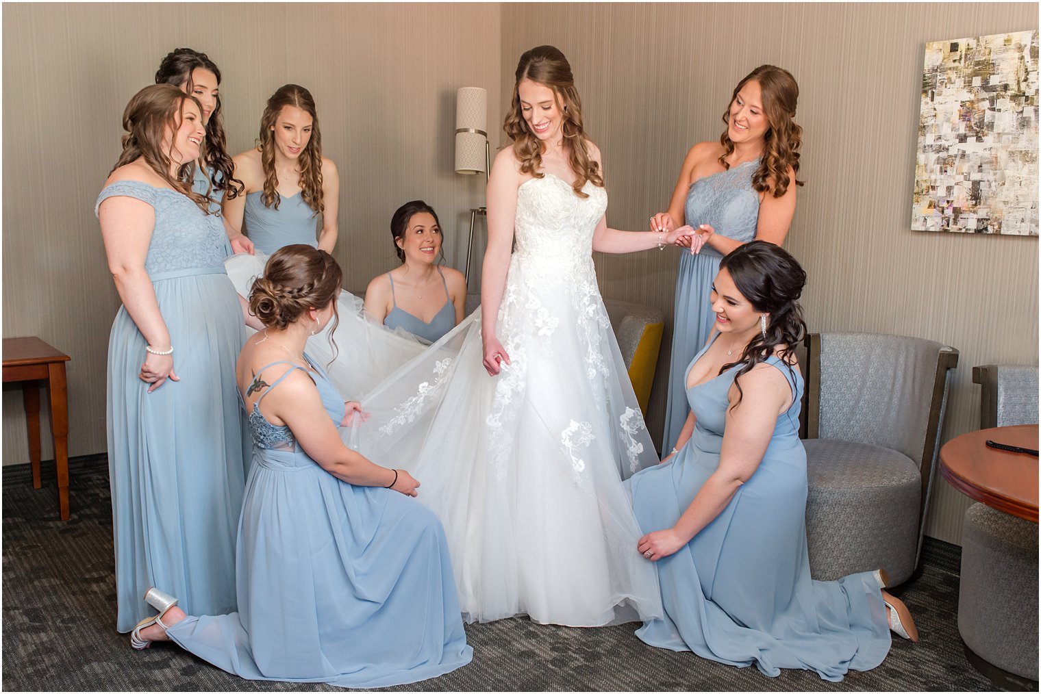 bridesmaids in light blue gowns help bride prepare for NJ wedding day