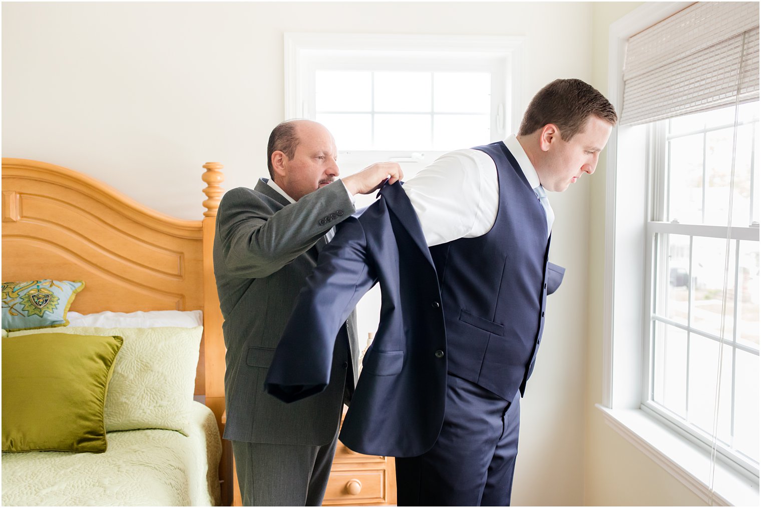 groom's father helps groom with suit jacket 