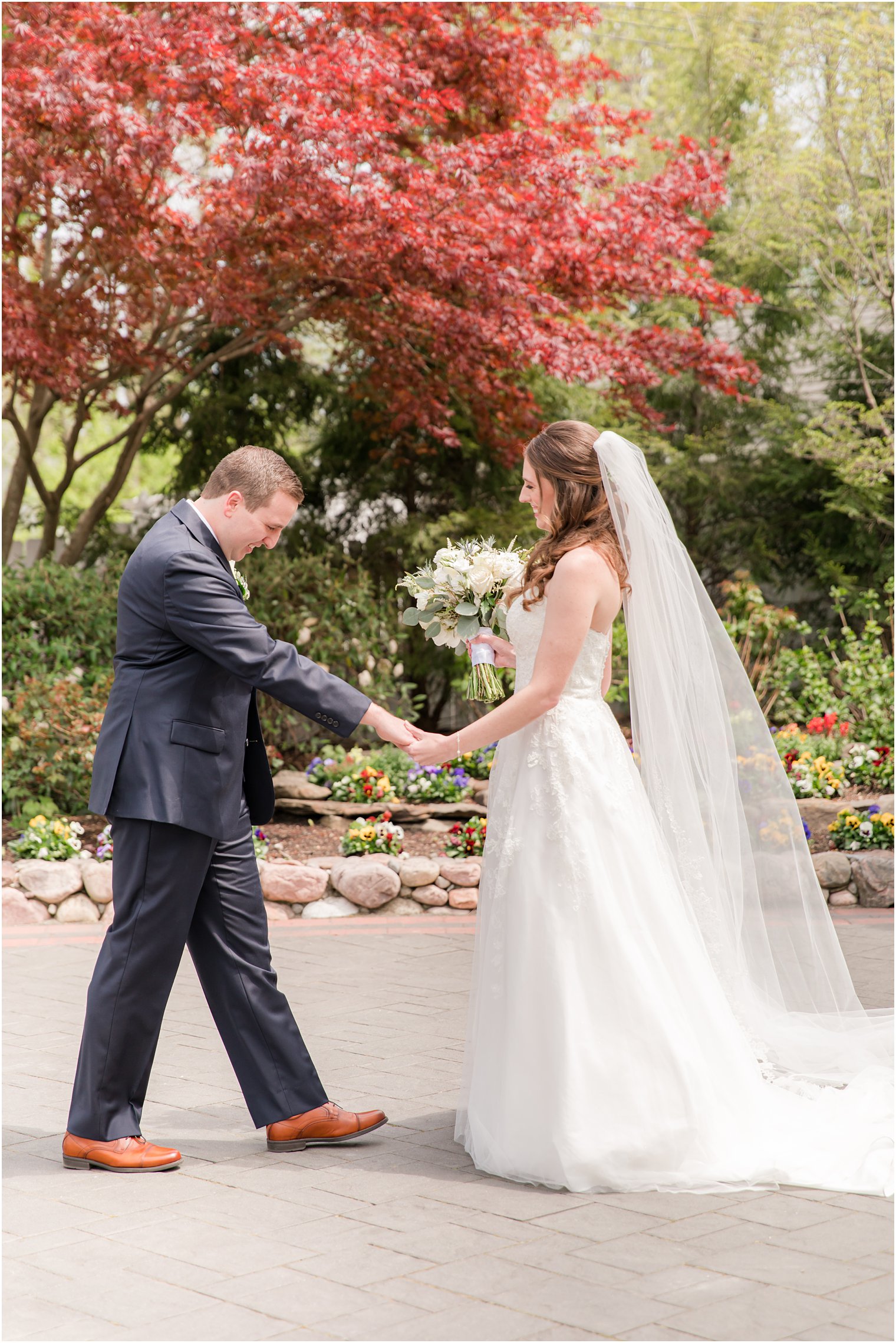 groom looks at bride's wedding dress during NJ first look 