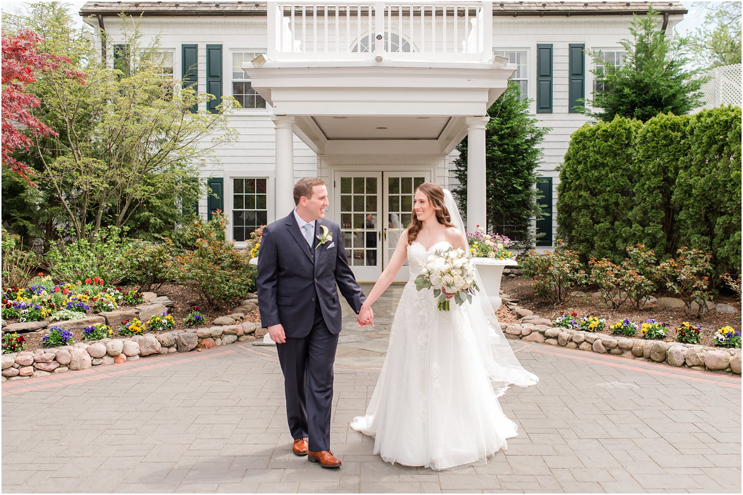 newlyweds walk in front of The English Manor holding hands 