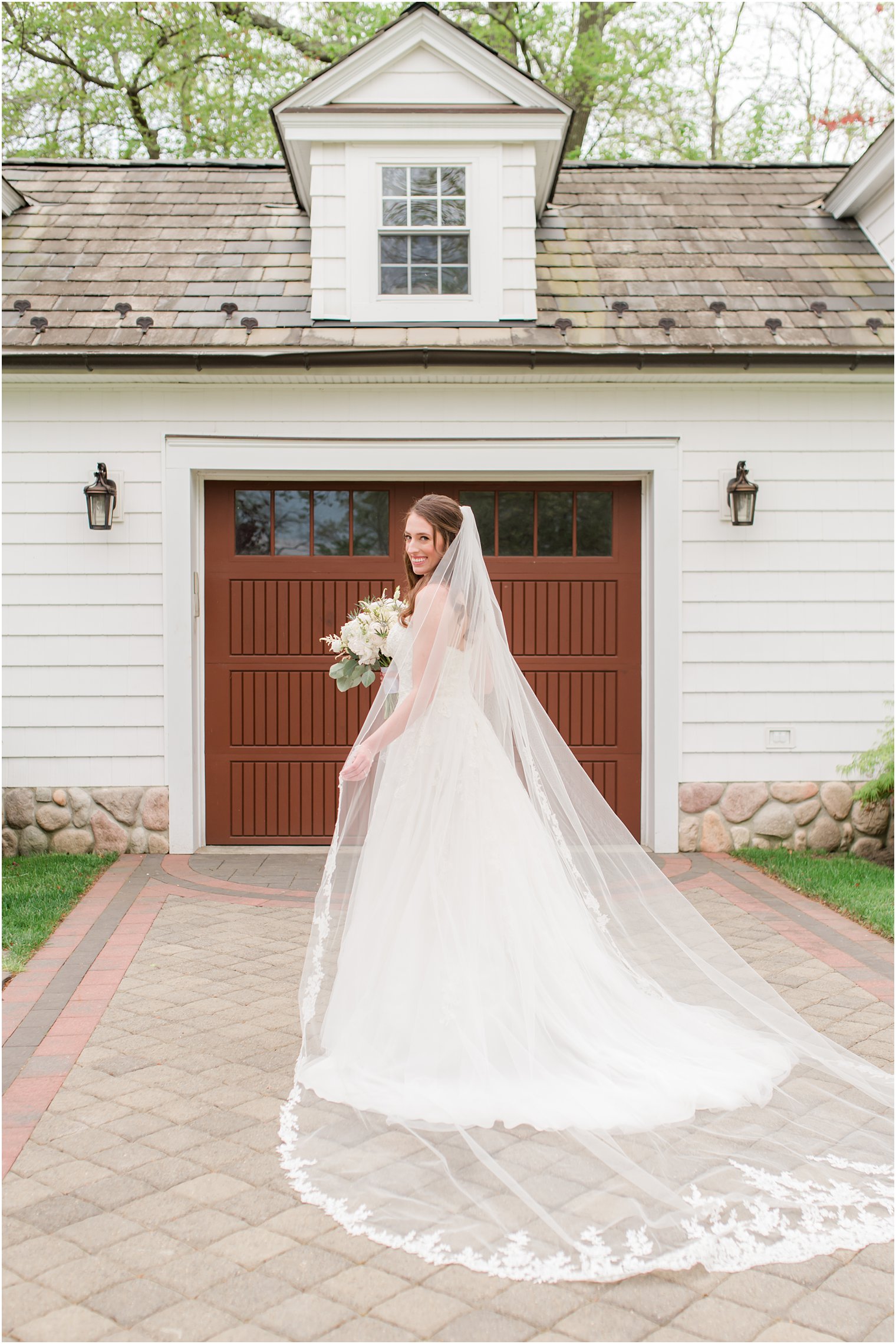 bridal portrait in driveway of The English Manor with veil spread out behind bride 