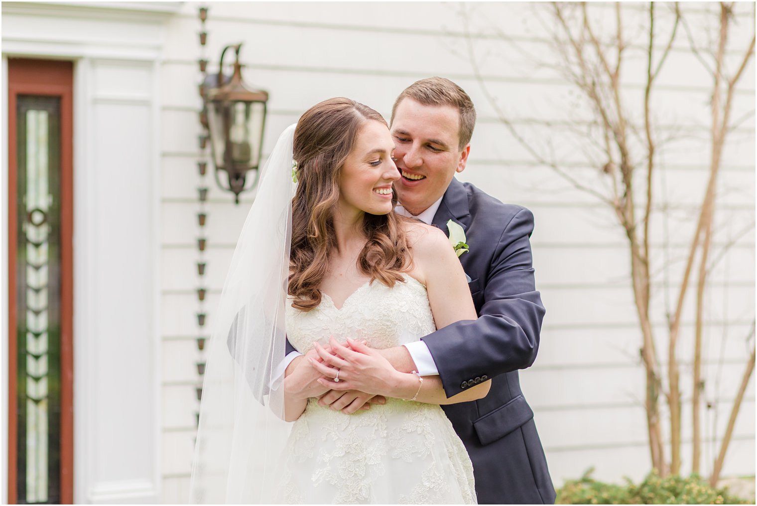 groom hugs bride from behind during spring English Manor wedding photos 