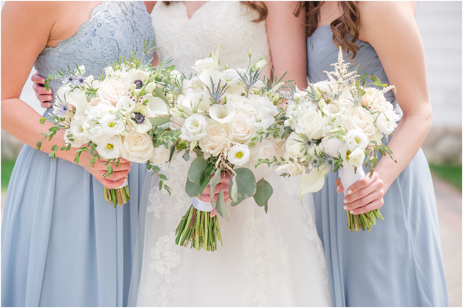 bride poses with bridesmaids in light blue gowns with white flowers 