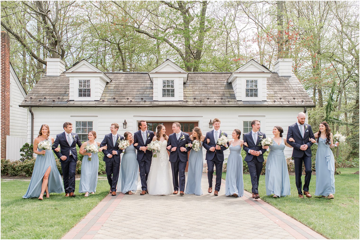 bride and groom walk with bridal party in navy suits and light blue dresses 