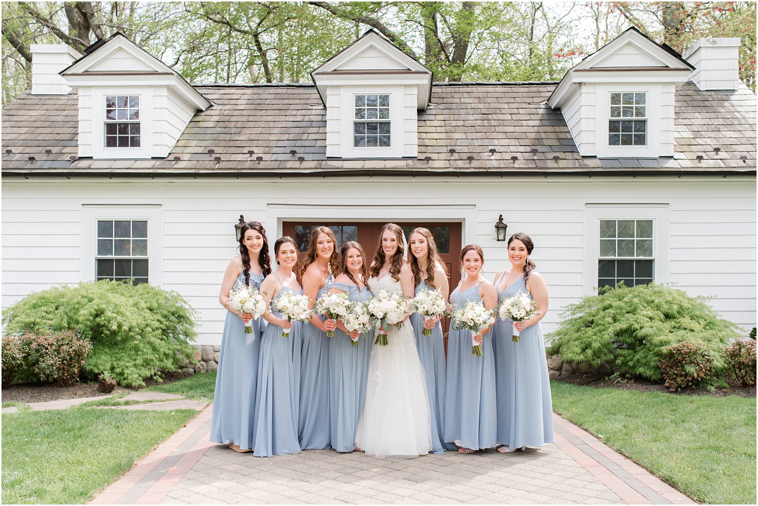 bride poses with bridesmaids in light blue gowns outside NJ wedding venue 