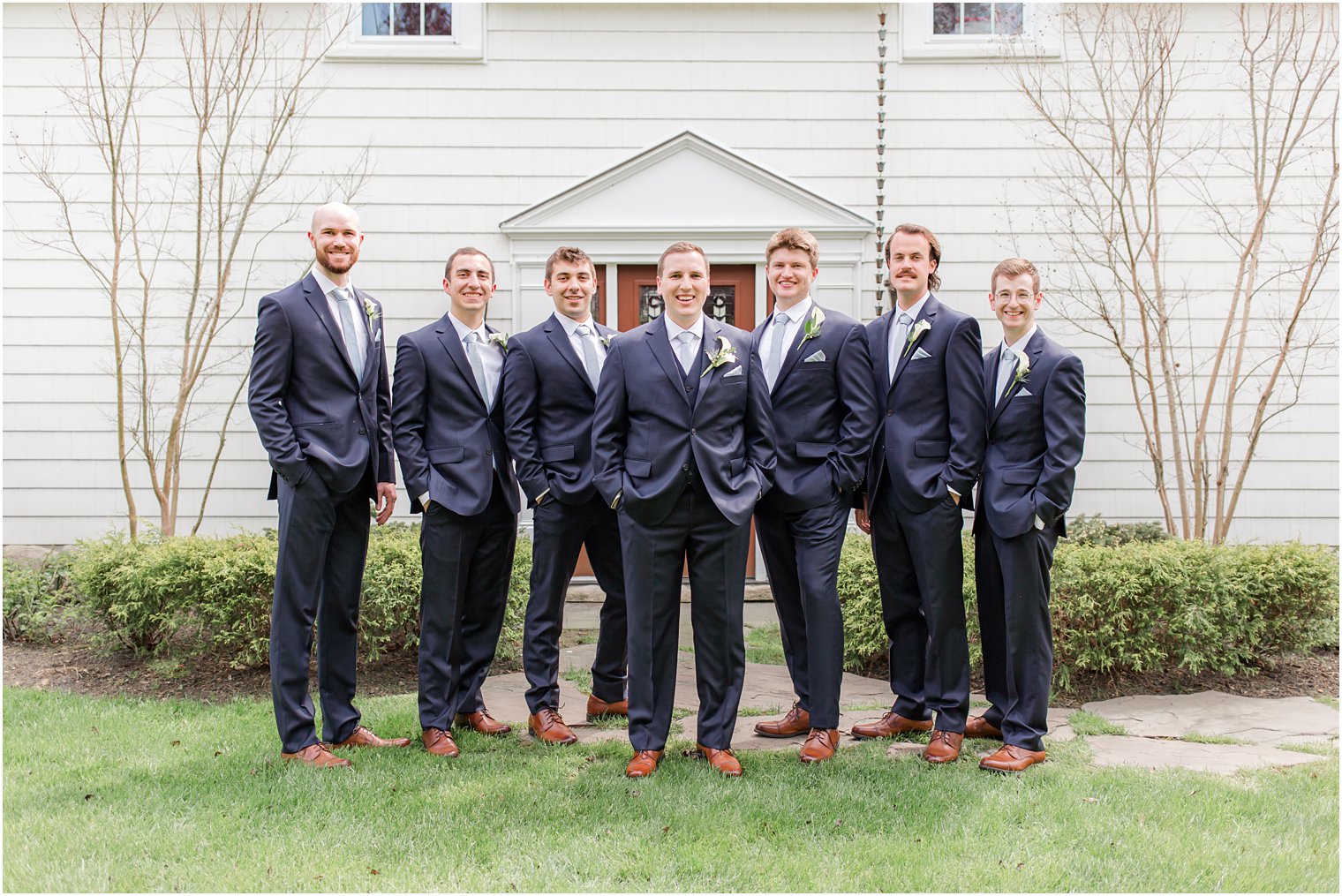 groom poses with groomsmen in blue suits 