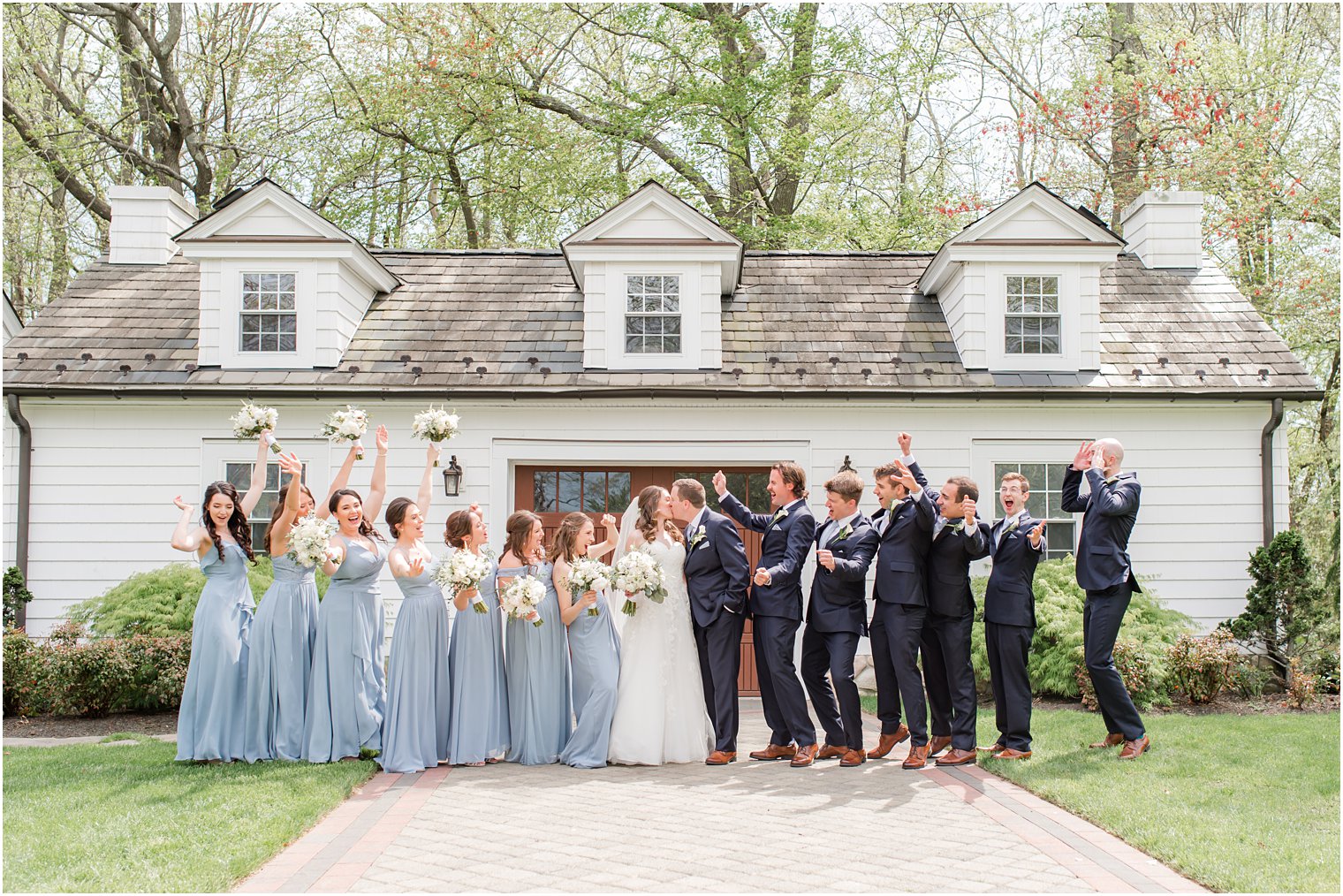 newlyweds kiss while bridal party cheers before NJ wedding