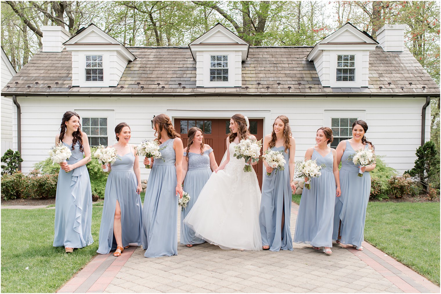 bride walks with bridesmaids in light blue gowns before spring English Manor wedding