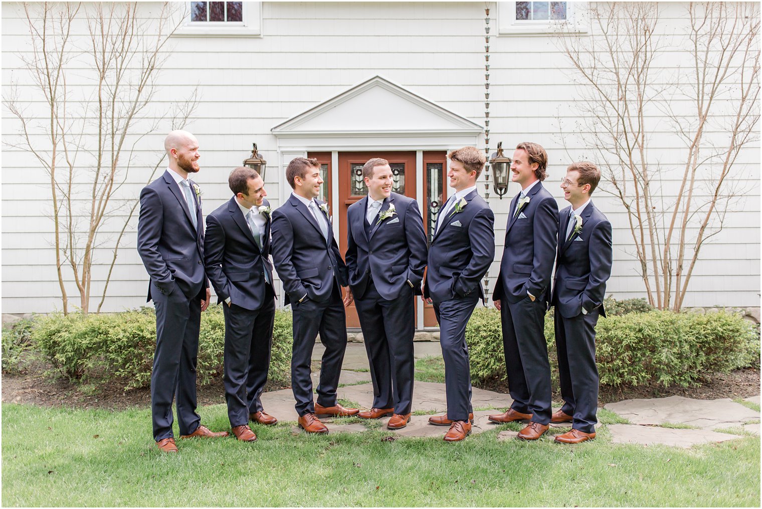 groom laughs with groomsmen in navy blue suits before NJ wedding 