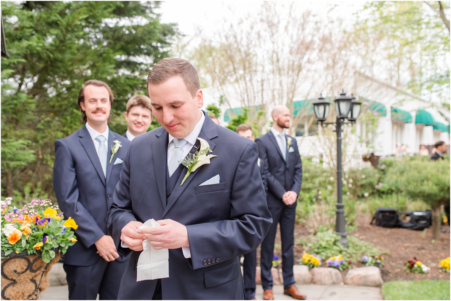 groom holds handkerchief before spring English Manor wedding ceremony 