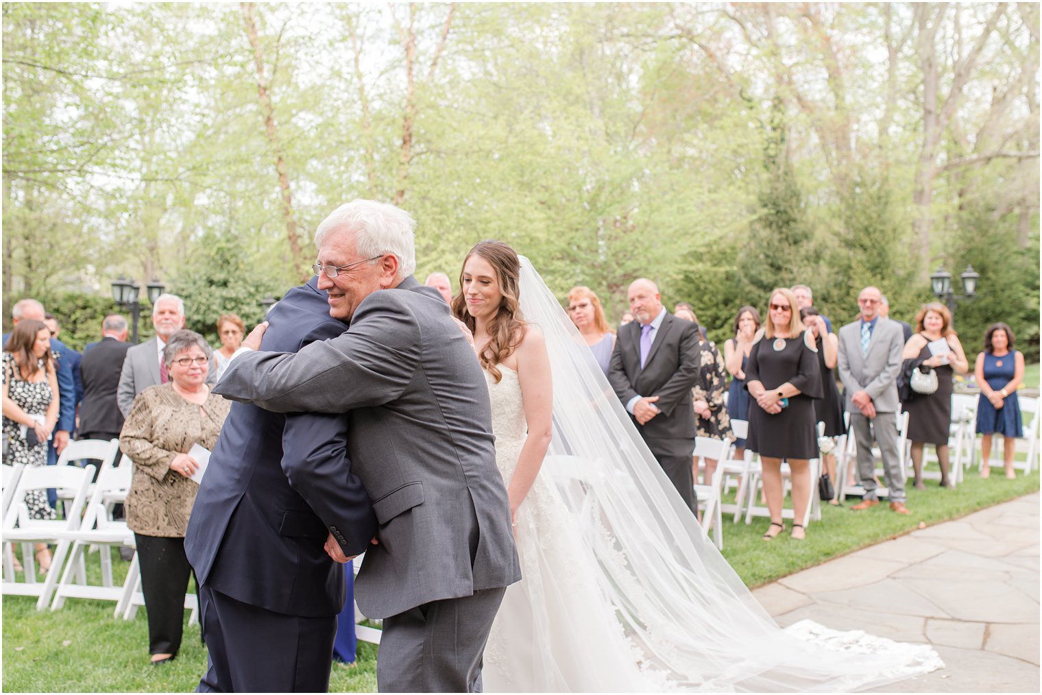 groom hugs dad of bride during NJ wedding ceremony 