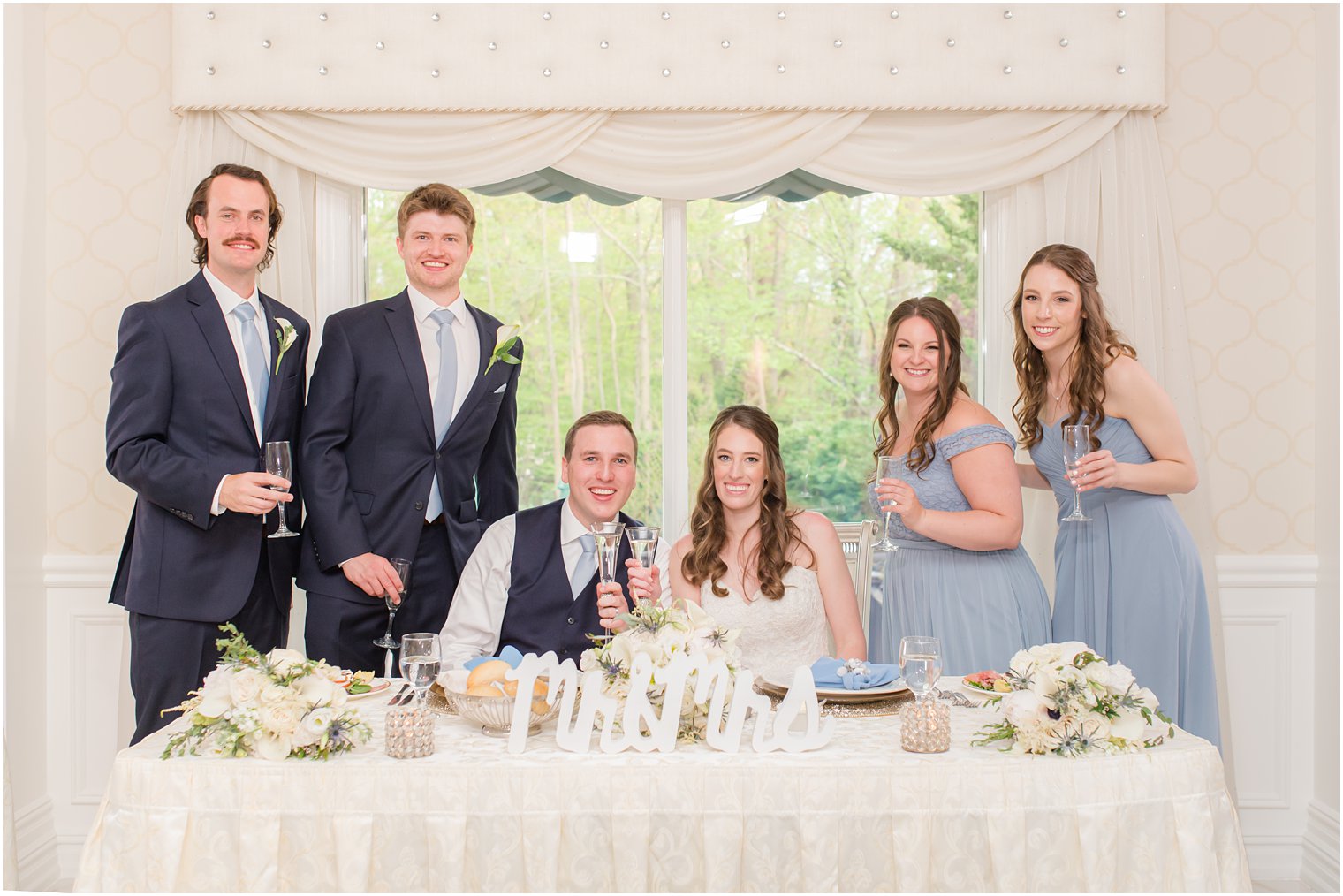 bride and groom pose with bridal party at sweetheart table in English Manor 