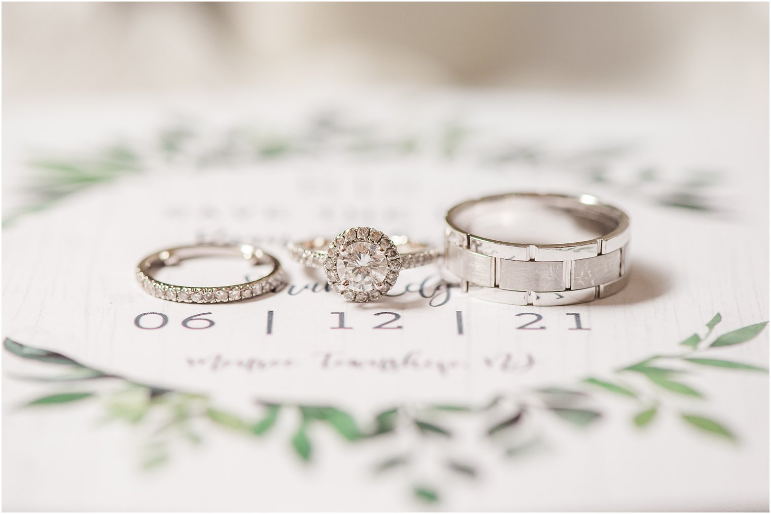 wedding bands rest on wedding invitation for Forsgate Country Club wedding day 