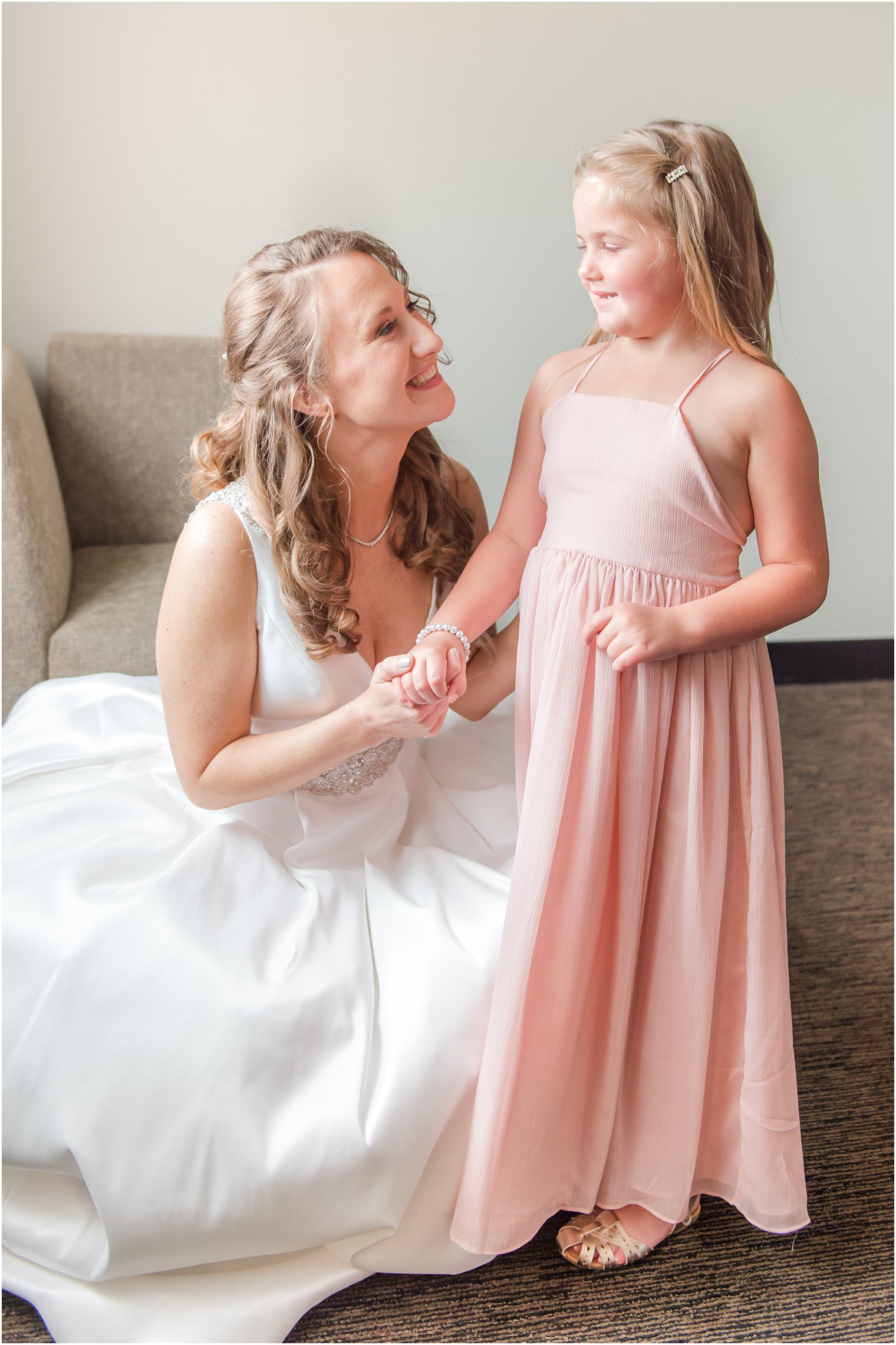 bride and flower girl smile together before NJ wedding