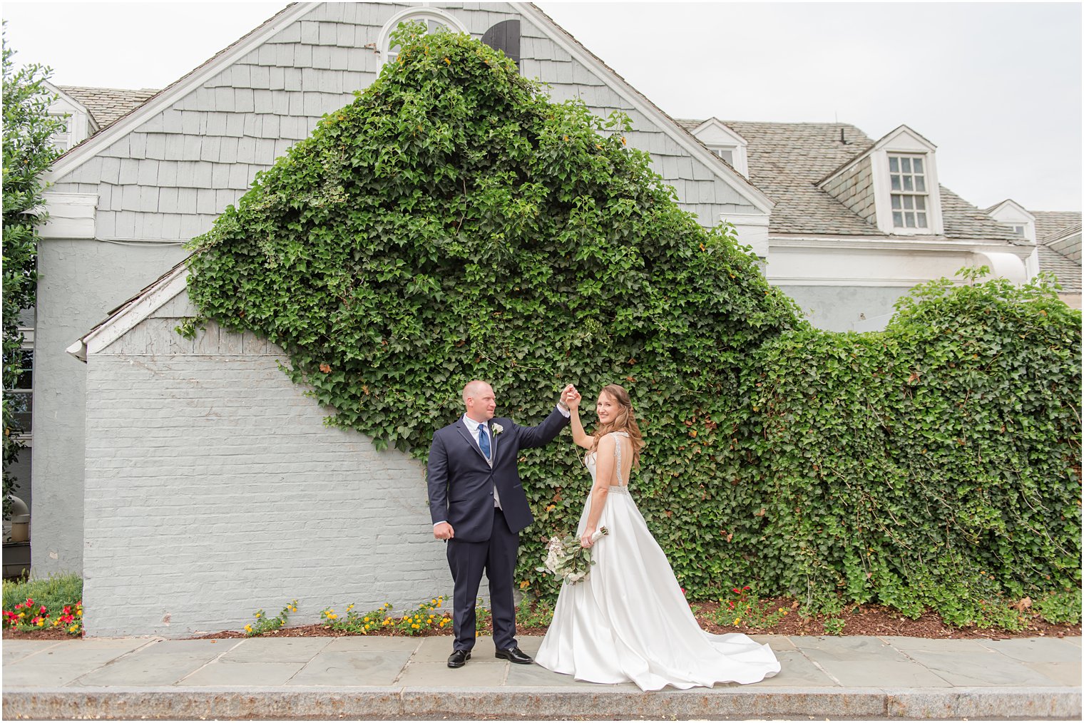 groom twirls bride by ivy covered wall at Forsgate Country Club
