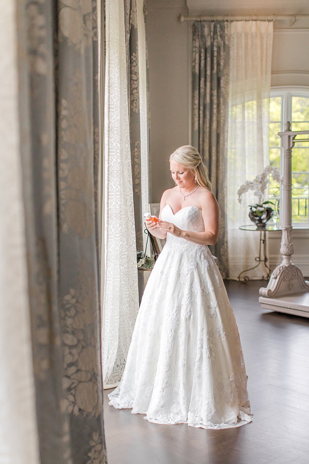 bride looks at perfume bottle in bridal suite at Park Chateau Estate