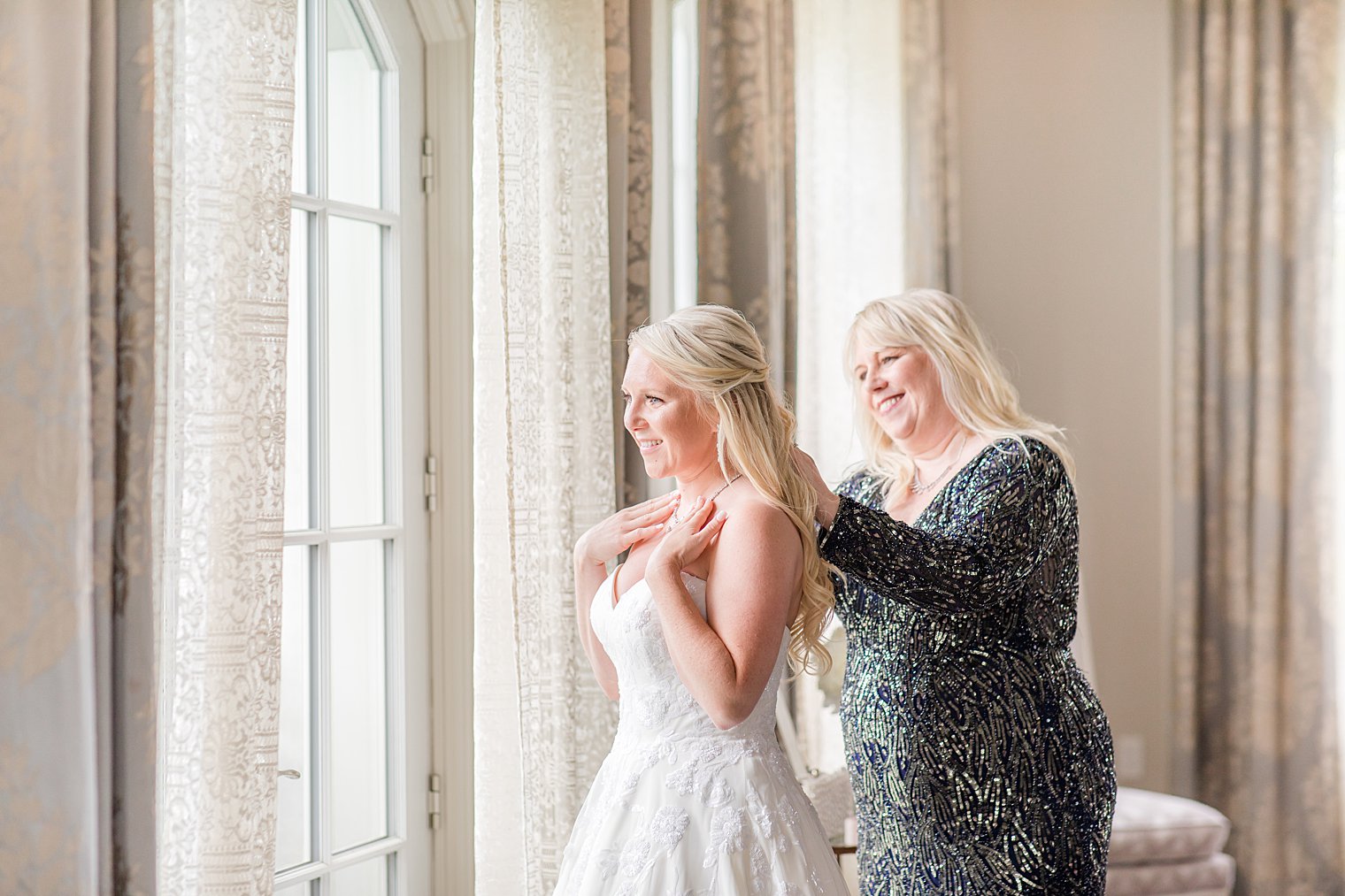 mother of bride helps with necklace on wedding day