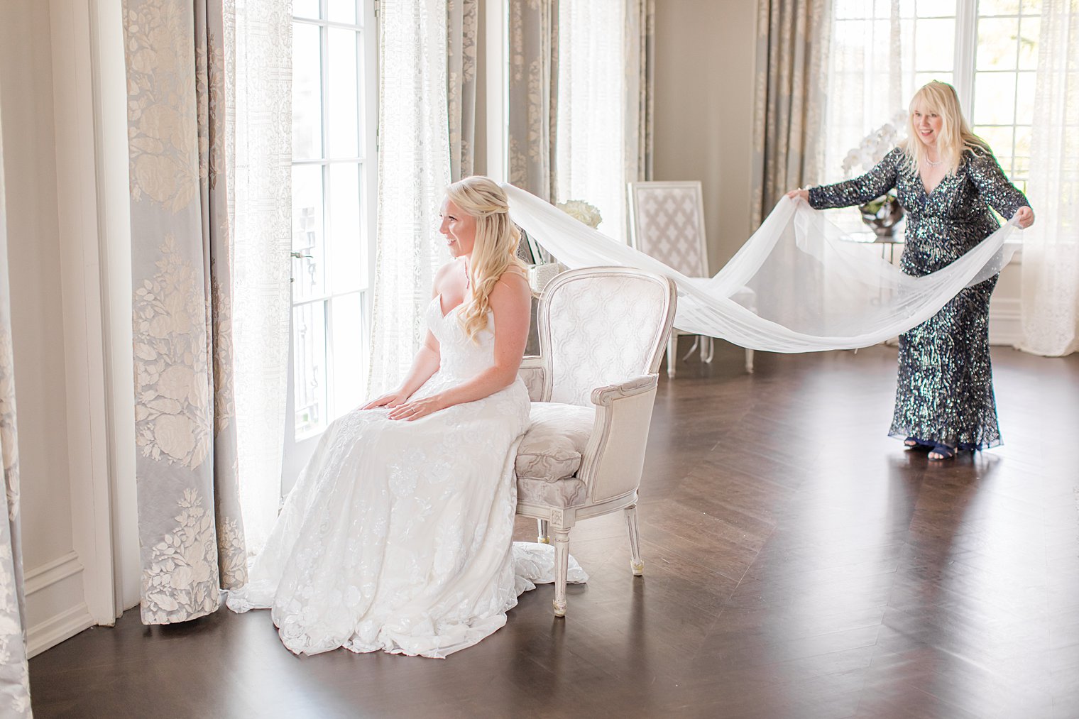 mother holds out veil for bride on wedding day