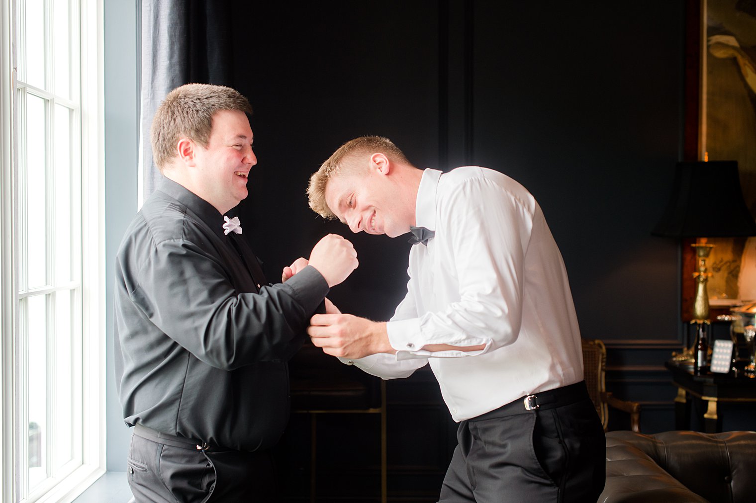 groomsman helps groom with cufflinks on wedding day