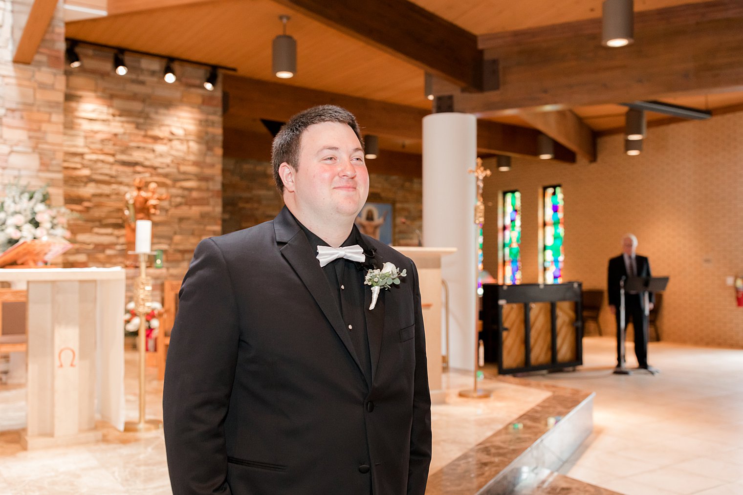 groom smiles looking at bride walking down aisle in church