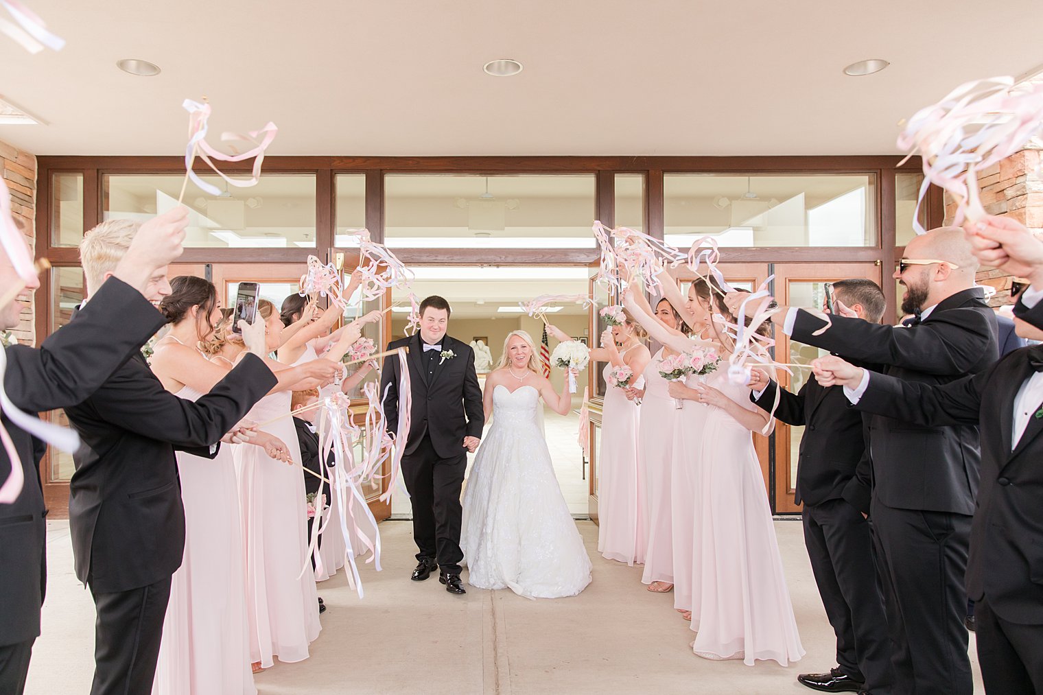 newlyweds leave church with bridal party shaking ribbons