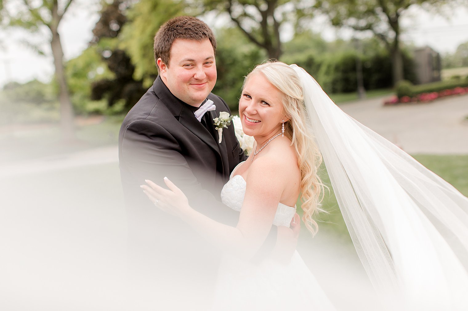 groom hugs bride with veil floating behind her at Park Chateau Estate