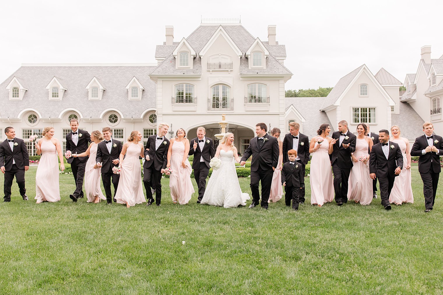 bride and groom walk with bridal party in pink and black attire