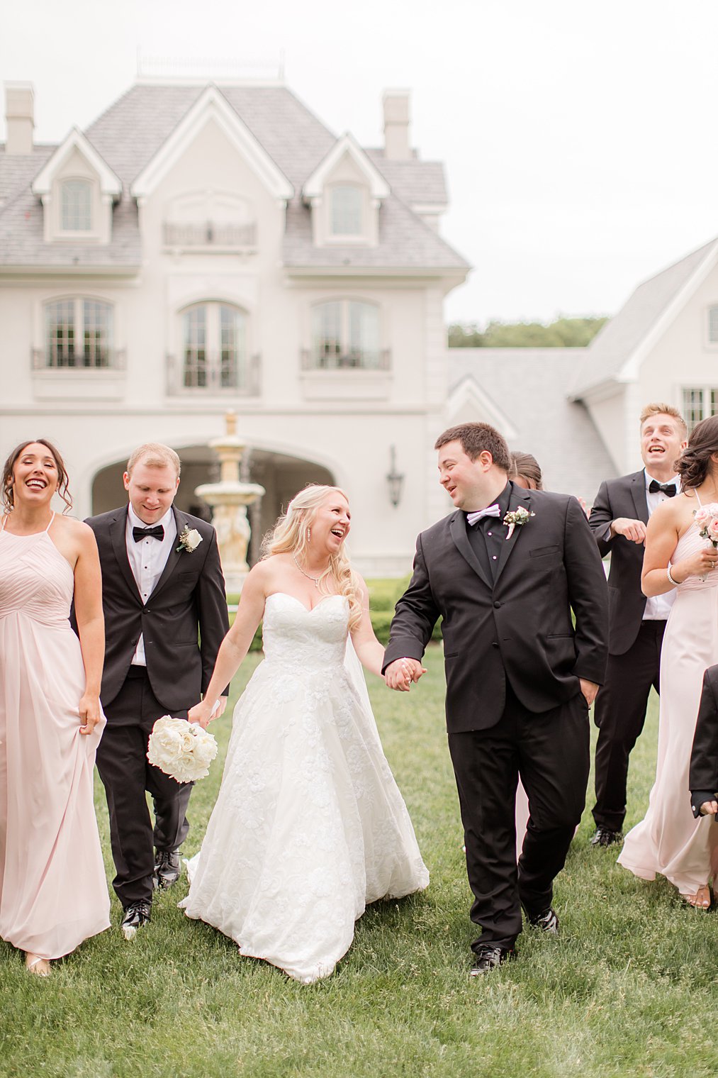 newlyweds laugh with bridal party on lawn at Park Chateau Estate