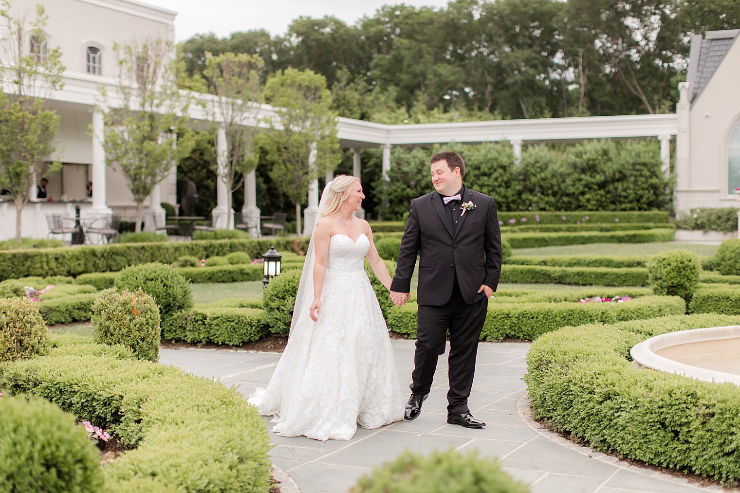 bride and groom hold hands walking through gardens at Park Chateau Estate