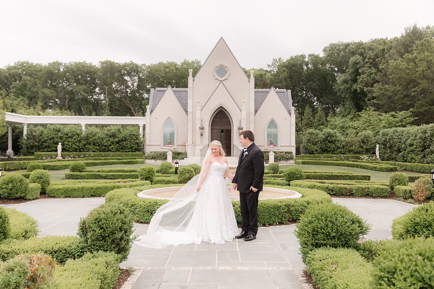 bride lifts veil in garden at Park Chateau Estate