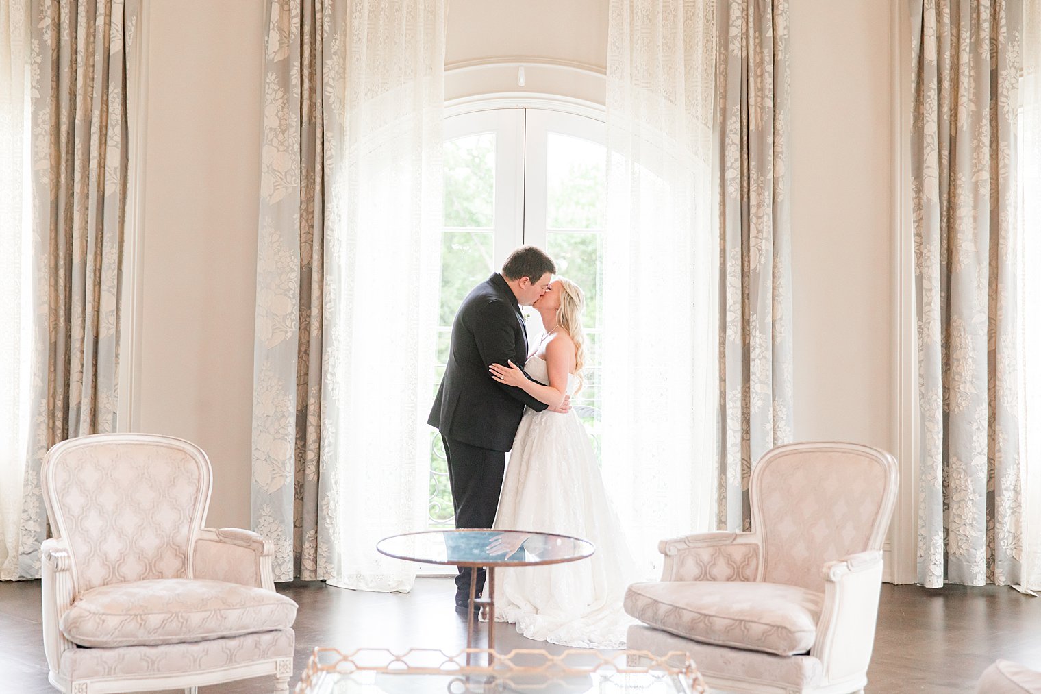 newlyweds kiss by window in Park Chateau Estate bridal suite