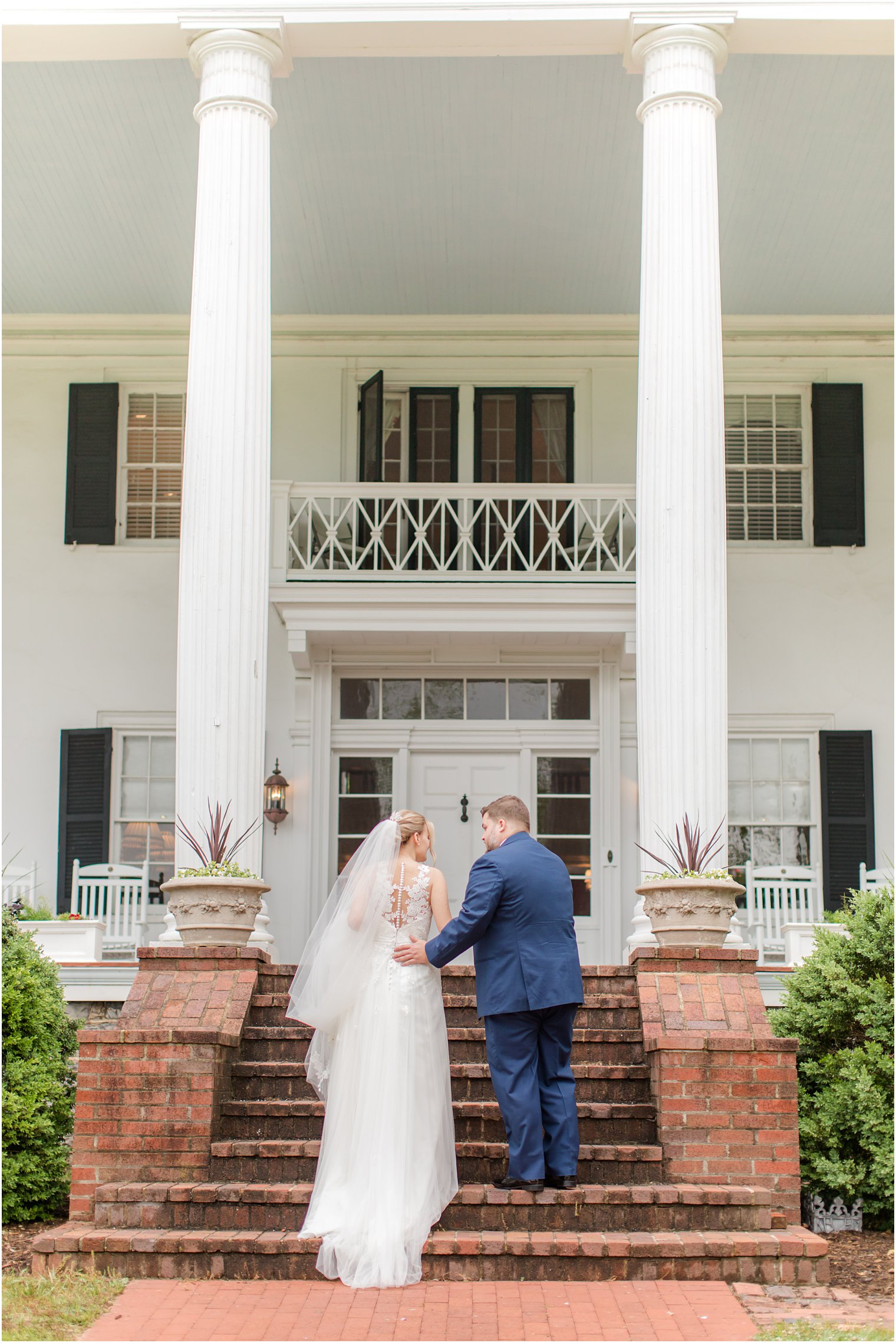 groom helps bride up steps outside Rosemont Manor