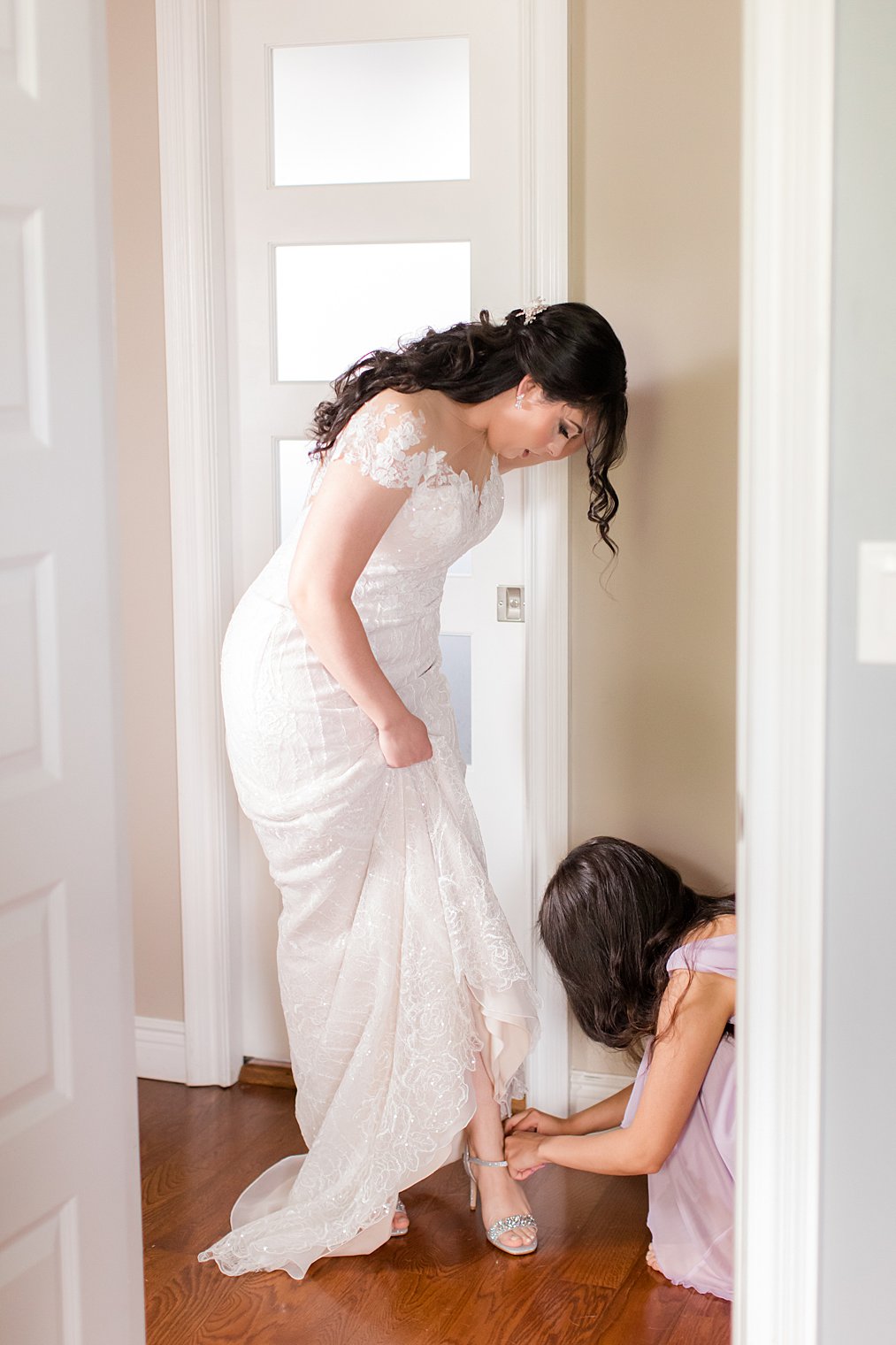 bridesmaid helps bride with shoes at home 