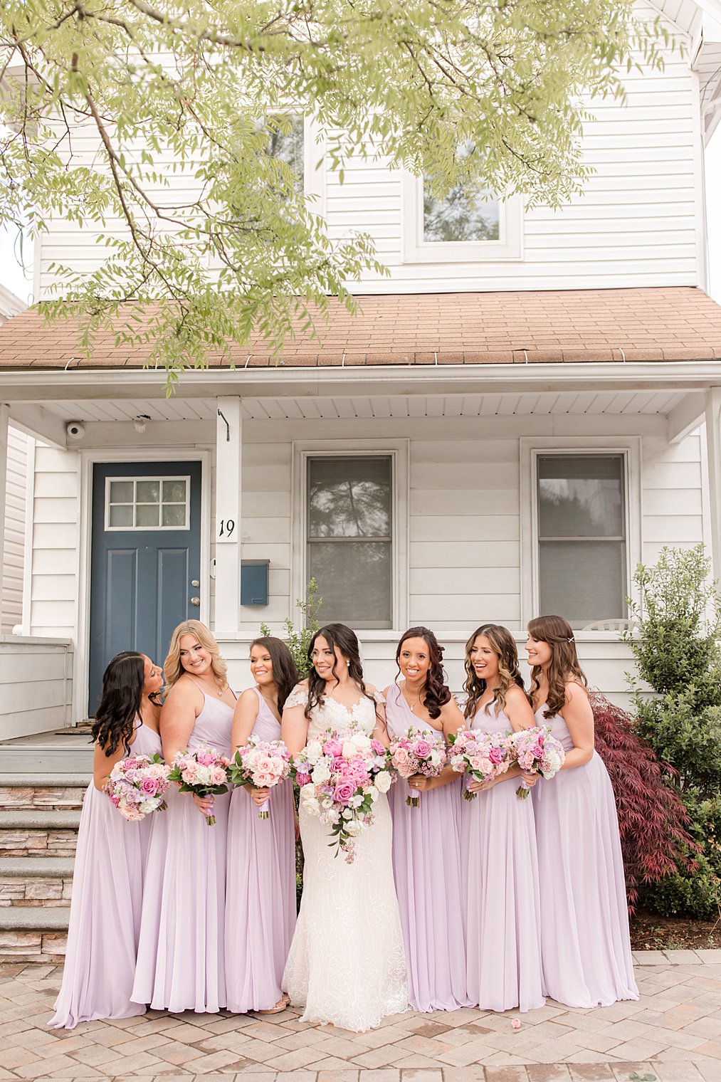 bride poses with bridesmaids in light purple gowns outside Staten Island home 