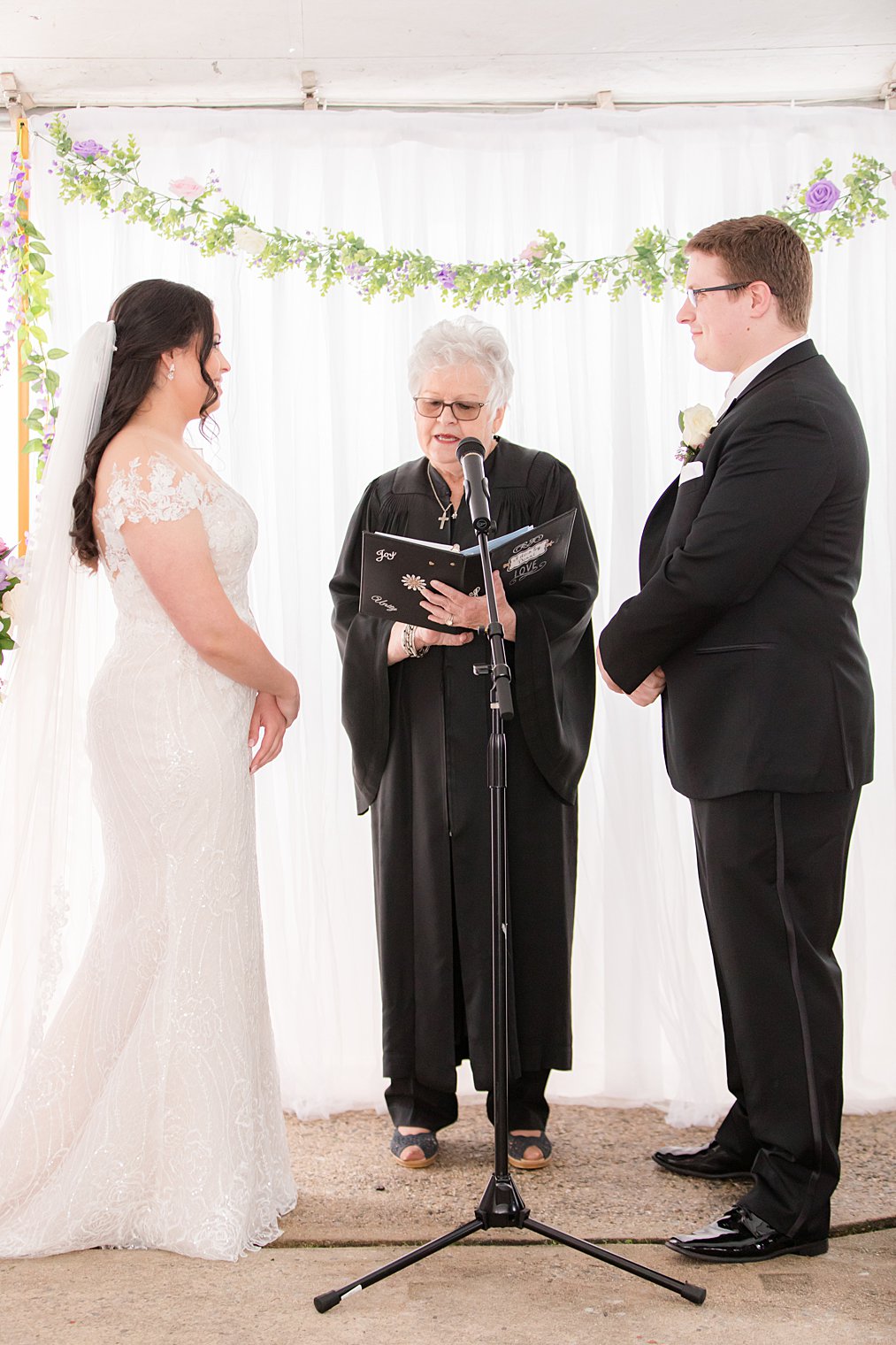 bride and groom listen to officiant read during backyard Staten Island wedding