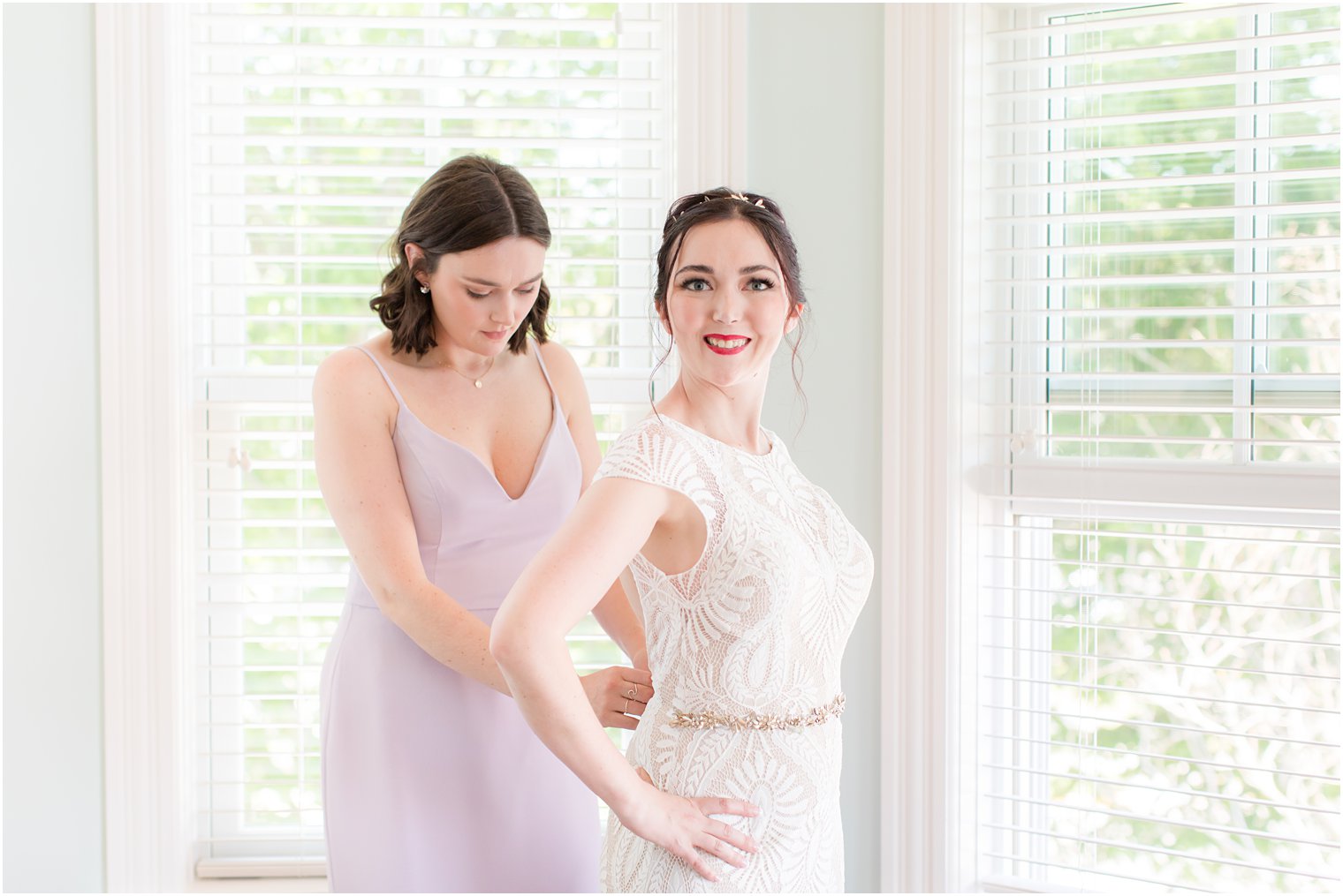 bride gets into wedding dress with bridesmaid's help